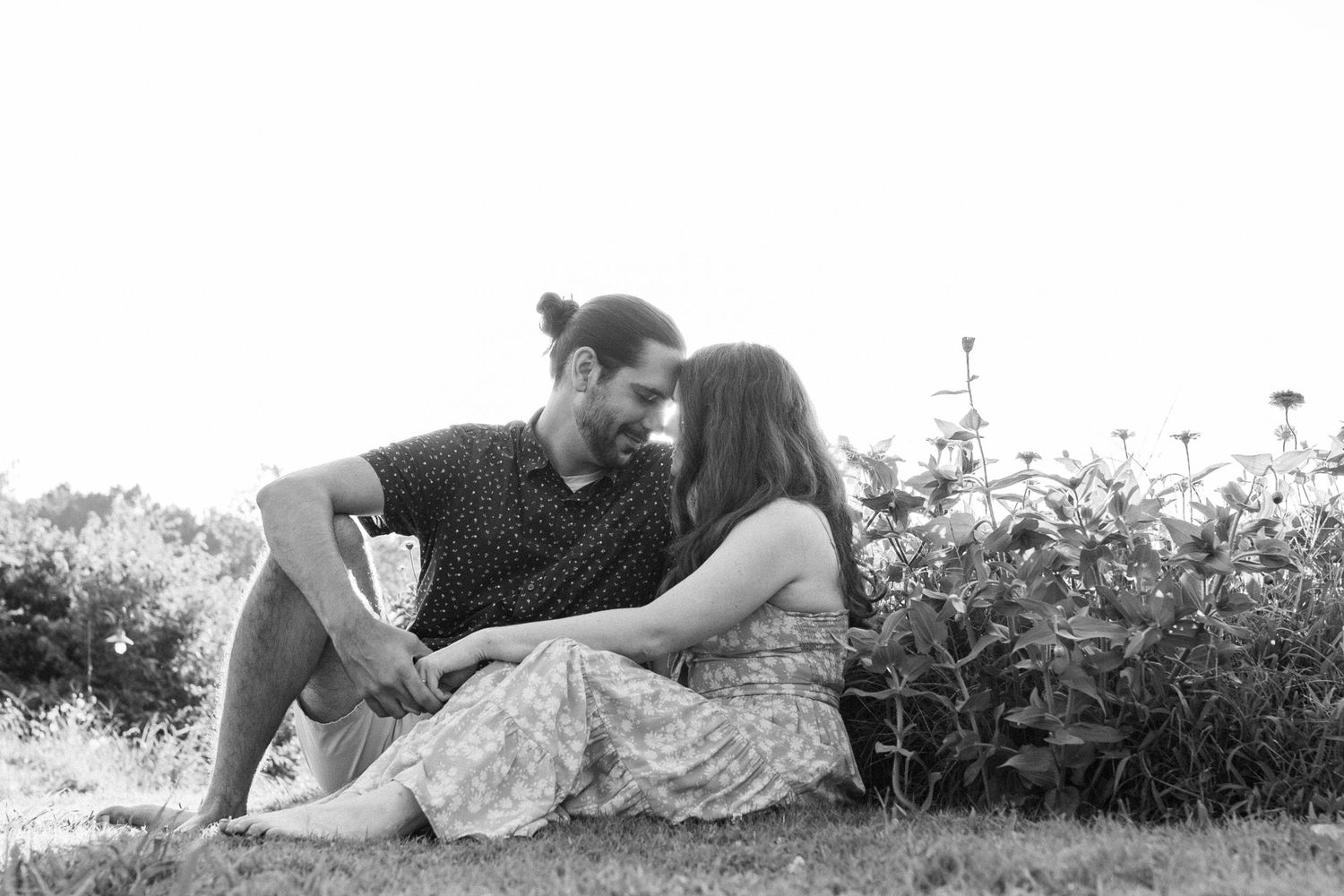 Black and white photo series shows subjects laying in floral fields wearing light colored dresses creating romantic imagery.