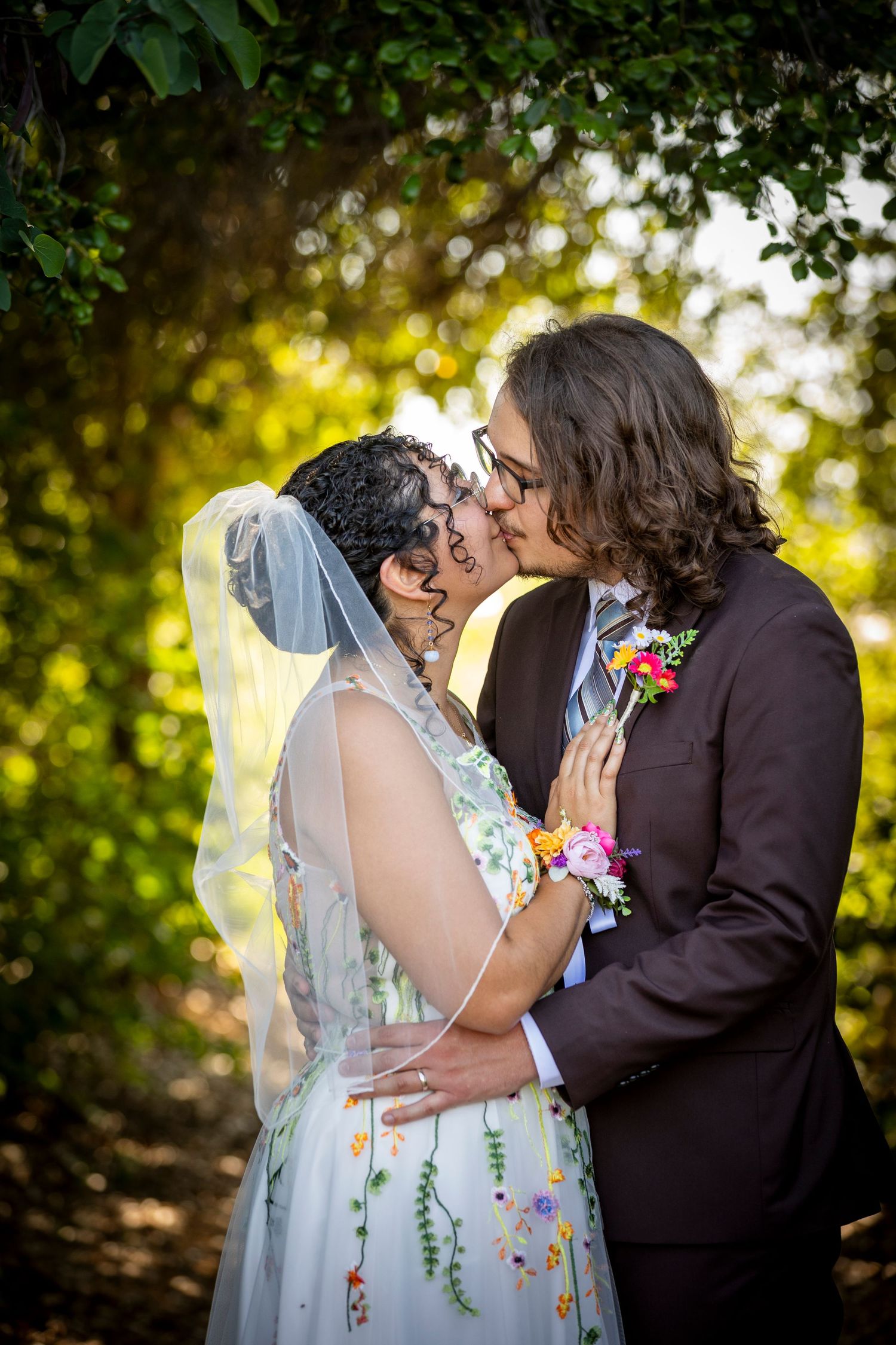 A romantic wedding kiss sequence captured outdoors with natural sunlight filtering through trees.