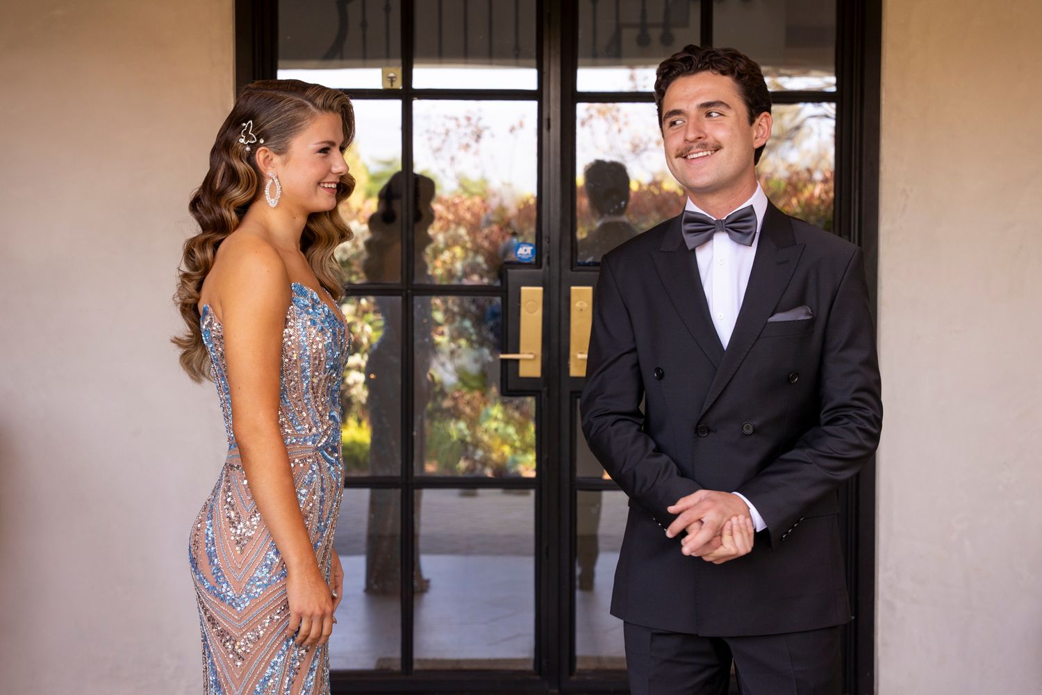 Prom couple sharing a First Look moment in elegant attire by glass doors. Redlands, CA.  Inland Empire Photographer, Redlands Business
