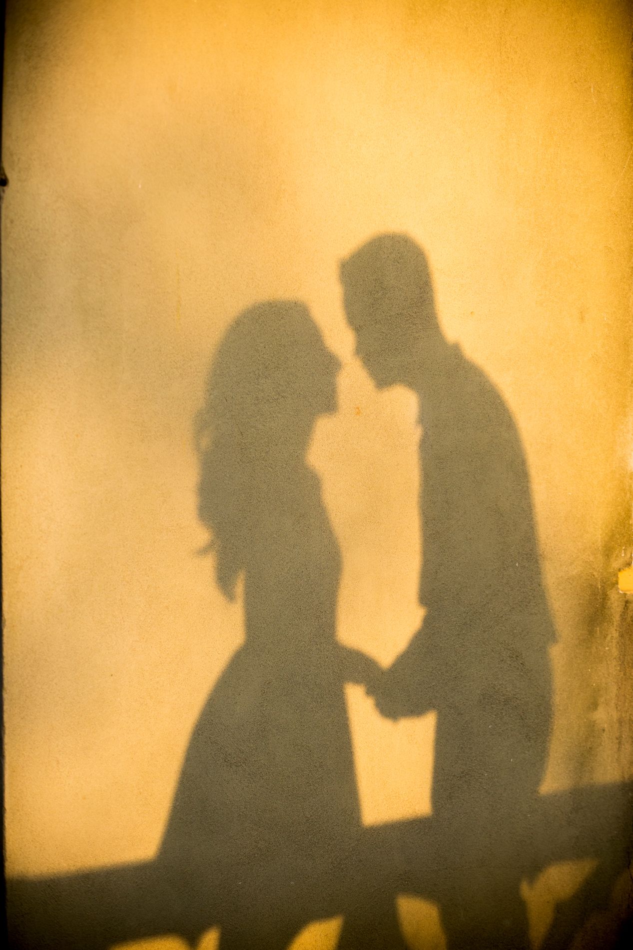 Romantic silhouette of a couple embracing against a warm golden background in vintage style.
