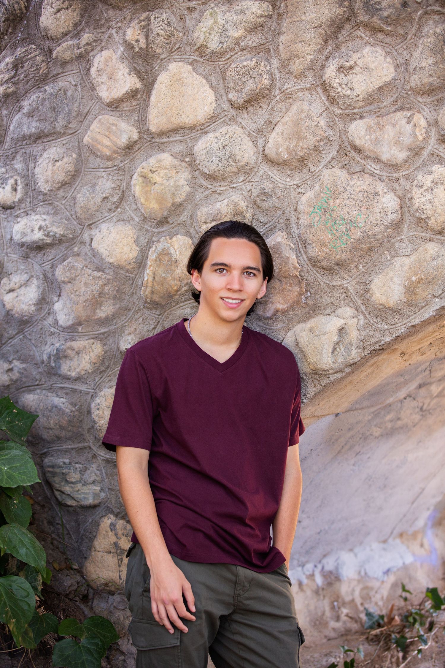 Casual Senior Portrait against a stone wall in an outdoor park setting. Riverside, CA.