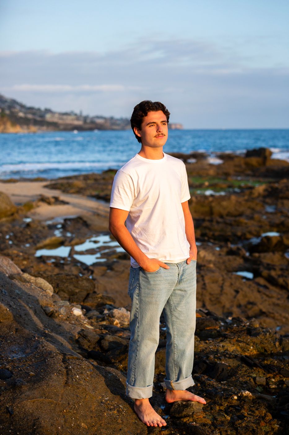 Casual beachside portrait with rocky coastline and ocean waves in background. Beach photography, Huntington Beach, Laguna Beach, Redlands