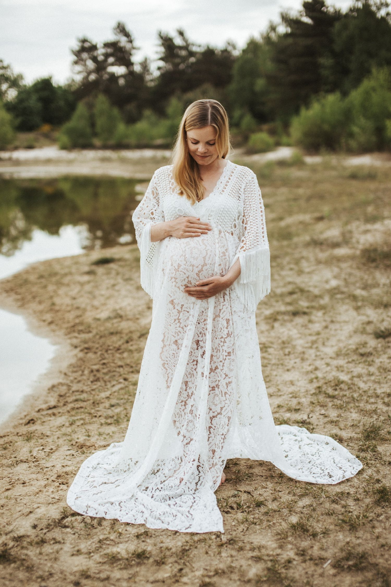 Schwangere Frau in weißem Kleid am See