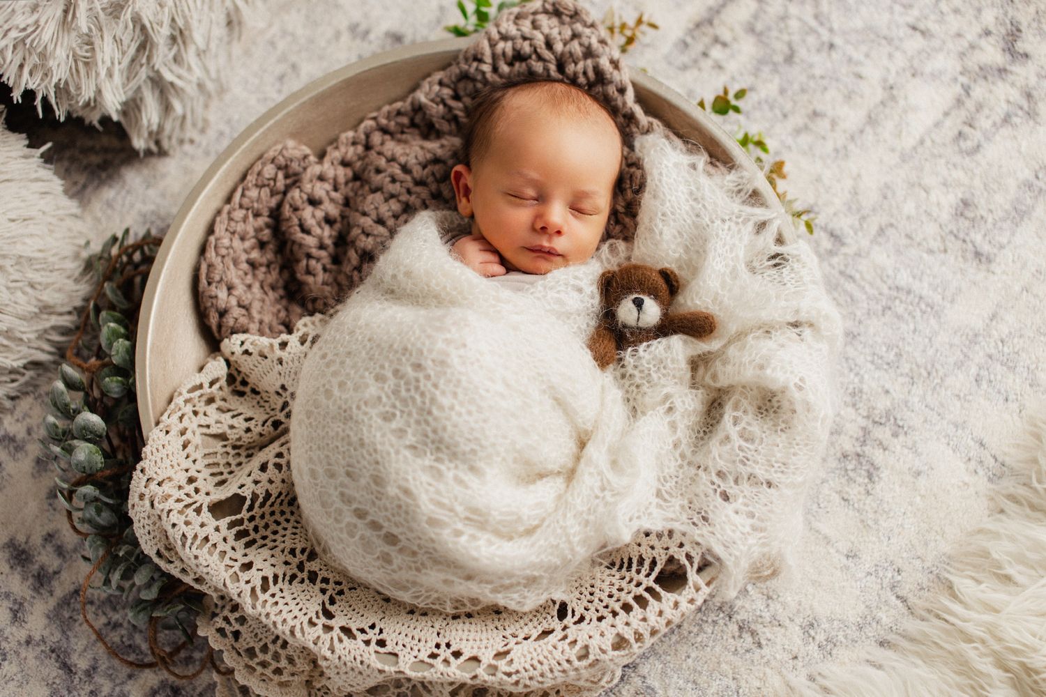 Baby mit Teddy in einem Newborn Set