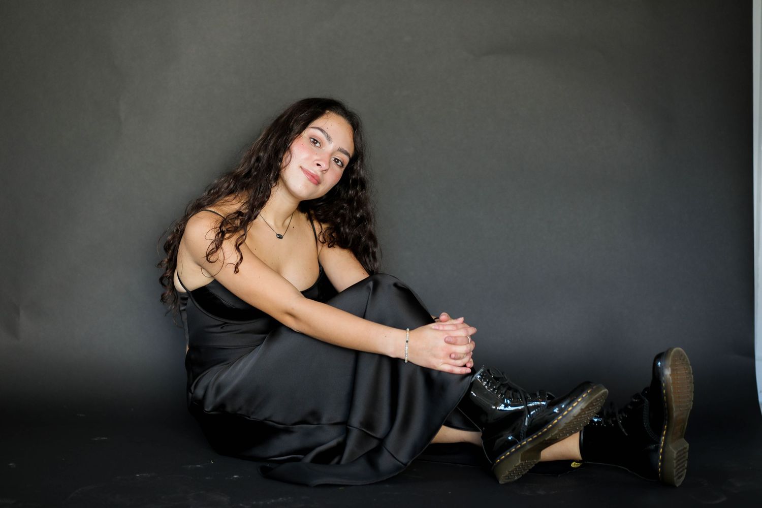 Artistic portrait in black dress against dark grey background.