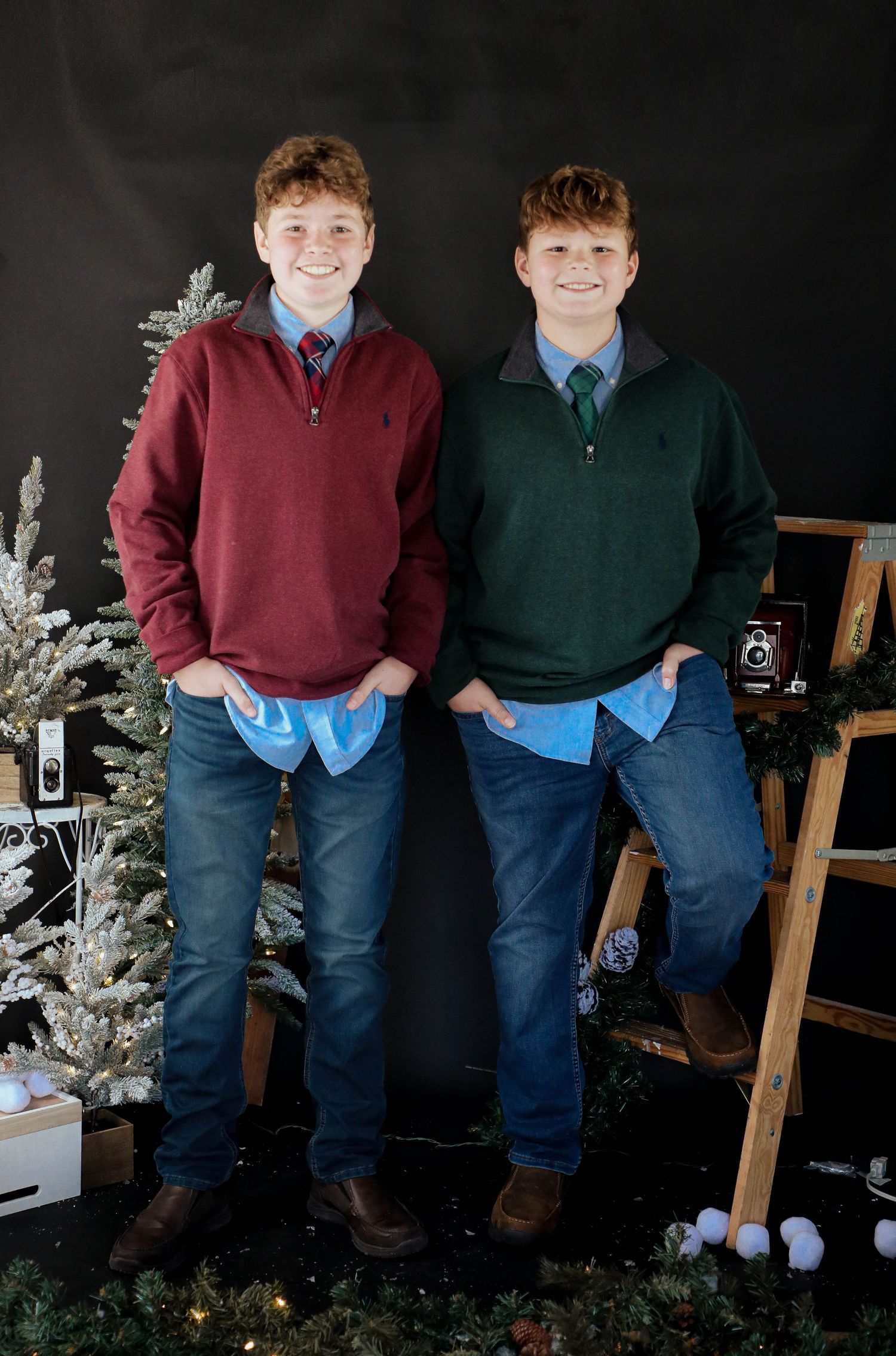 Holiday portrait with matching sweaters in burgundy and green against Christmas backdrop.