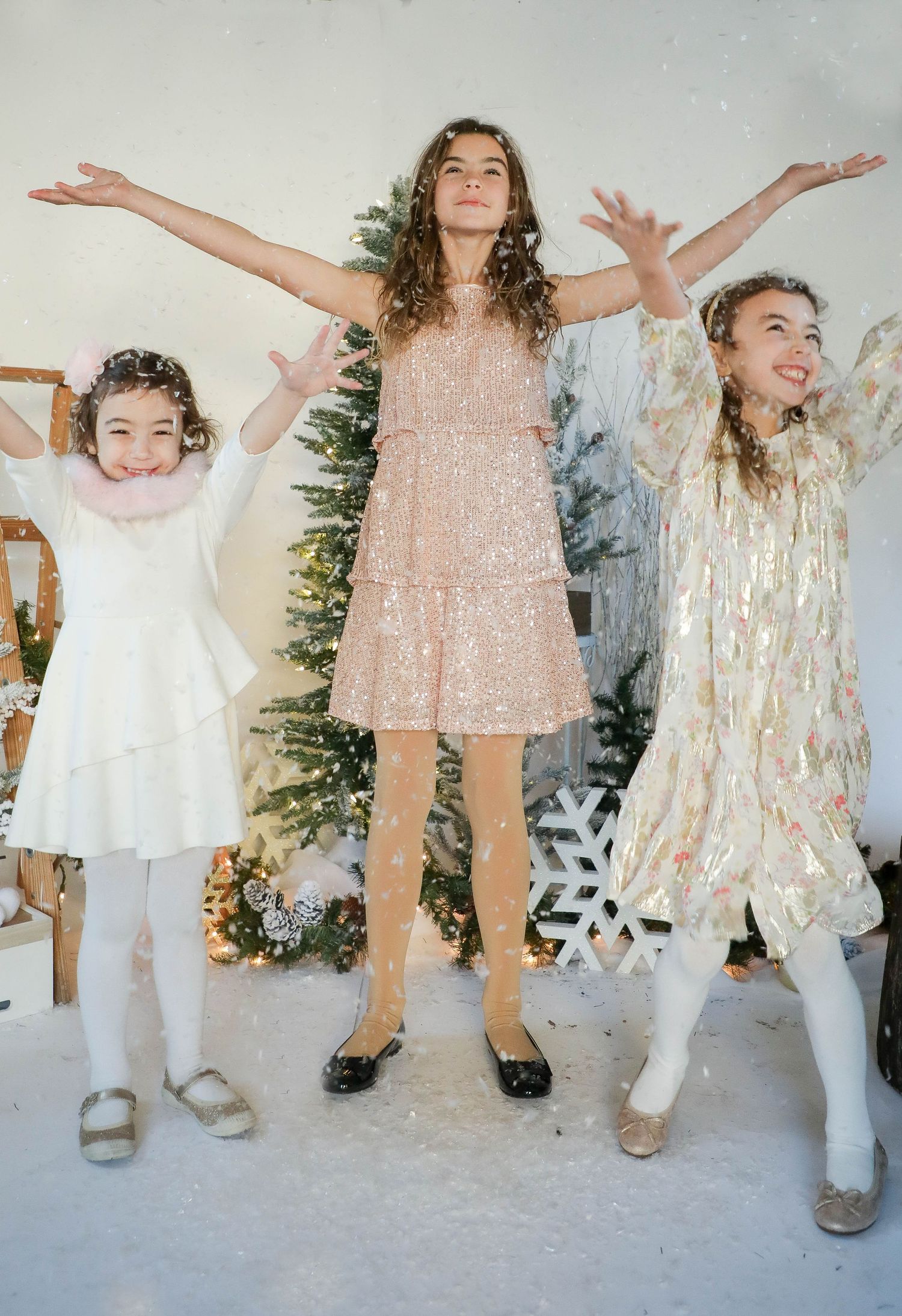 Three festive party dresses in sparkly gold and white celebrate against a snowy winter backdrop.