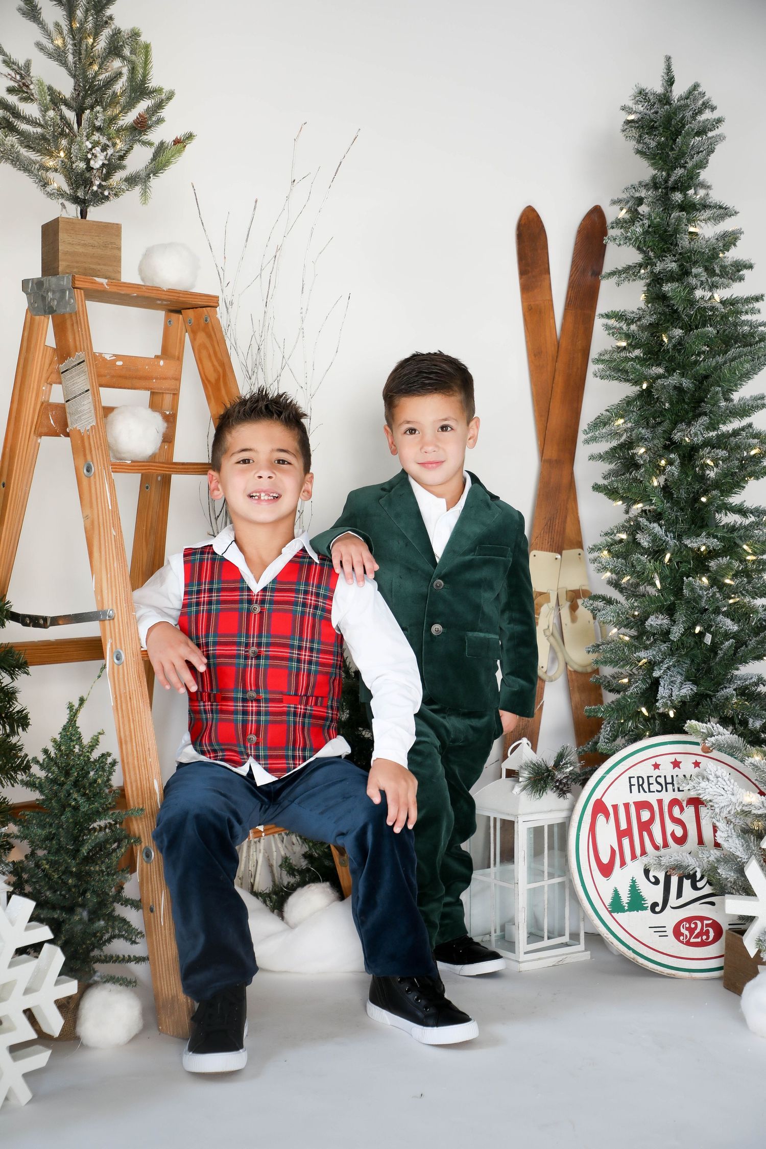 A festive holiday portrait setup with decorative Christmas tree, wooden ladder, vintage skis and rustic lantern.