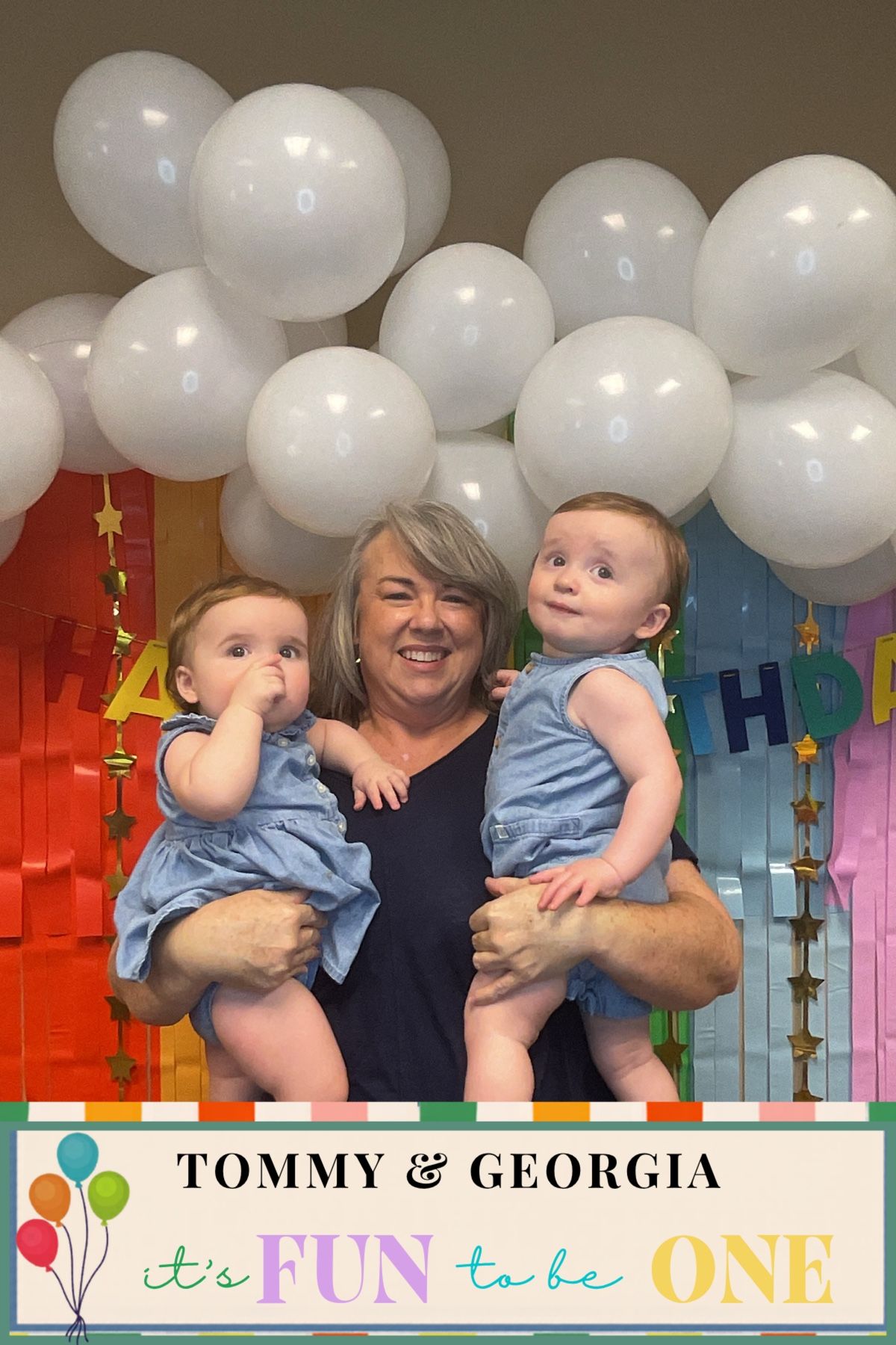 Grandmother holding twin babies in blue outfits at Tommy & Georgia's fun first birthday party.