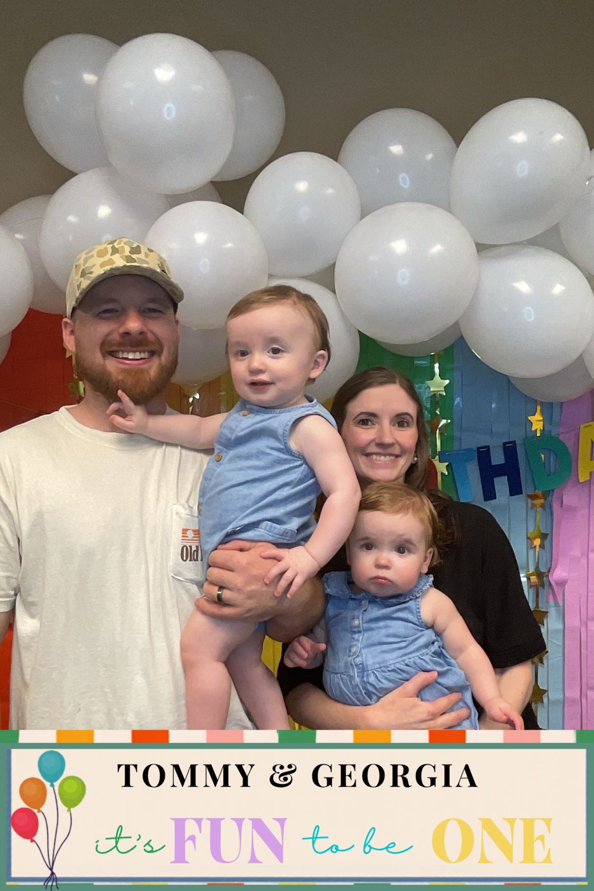 Parents holding twin babies in blue outfits at Tommy & Georgia's first birthday party.