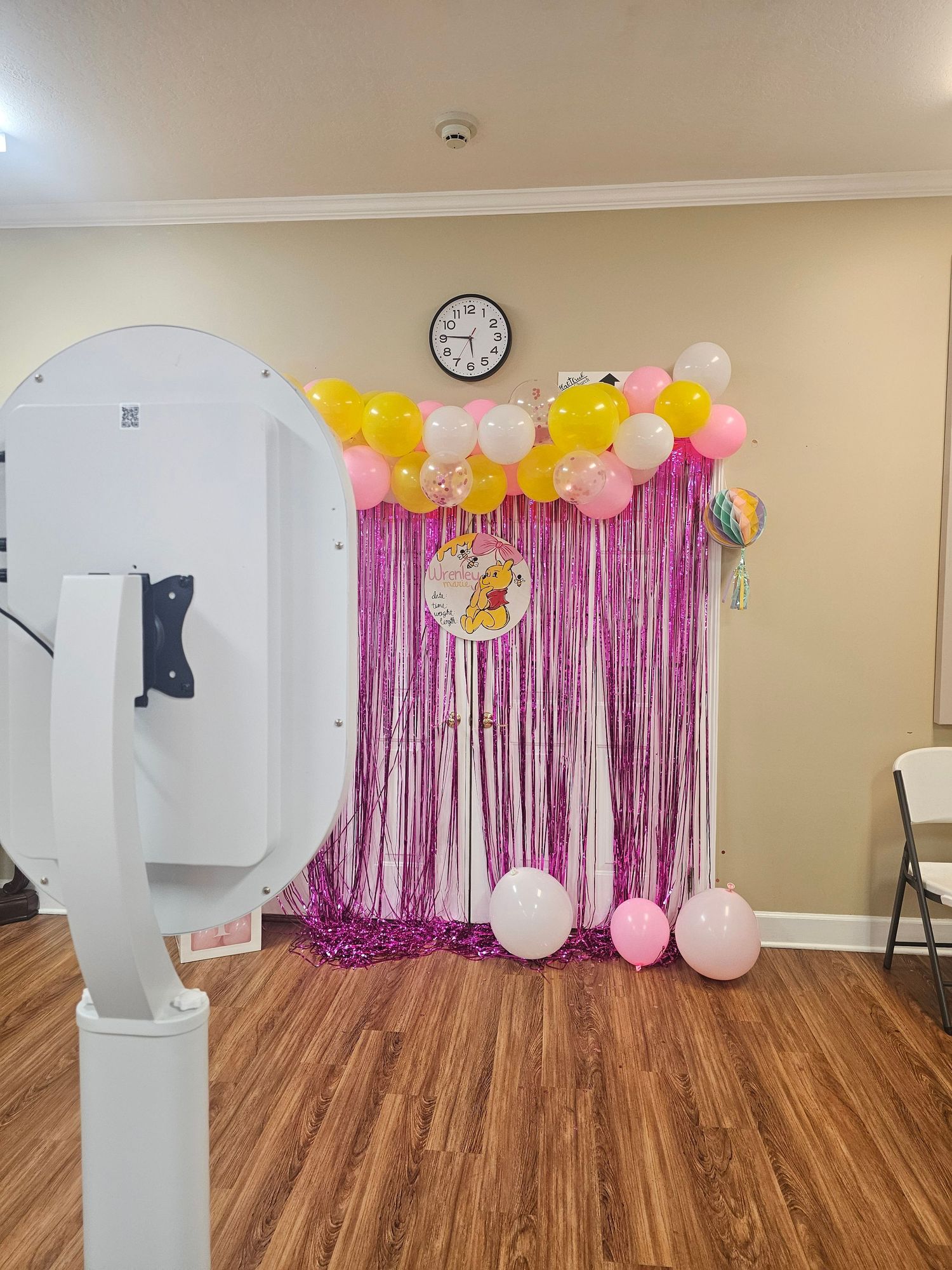 Pink fringe backdrop with colorful balloons and Winnie the Pooh balloon for a birthday party photo booth setup.
