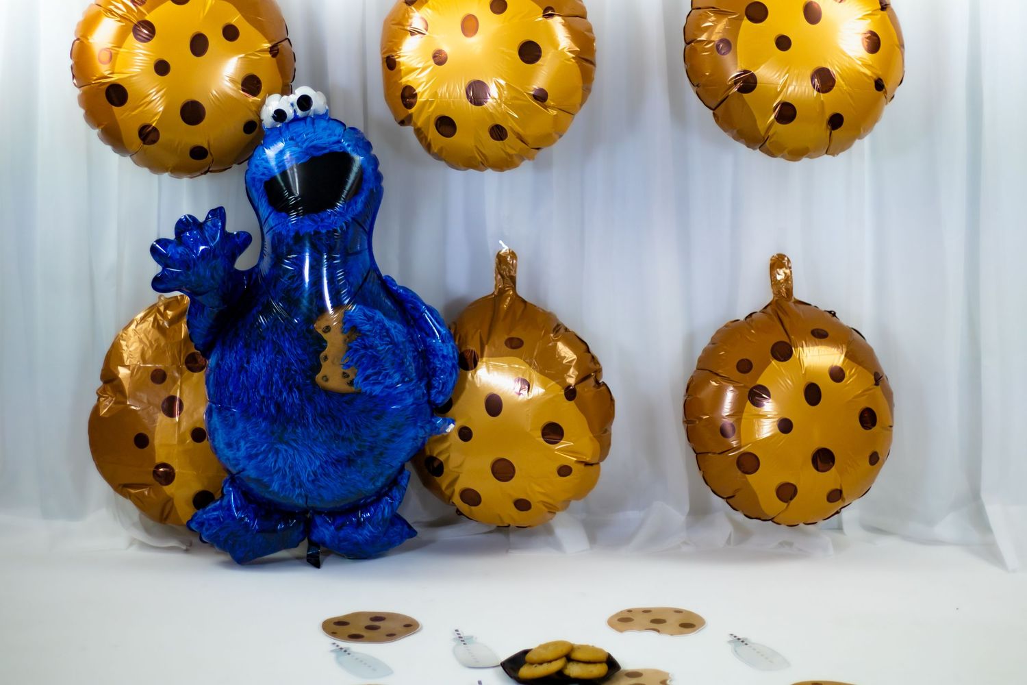 Cookie Monster balloon display with chocolate chip cookie balloons for a Sesame Street baby party.