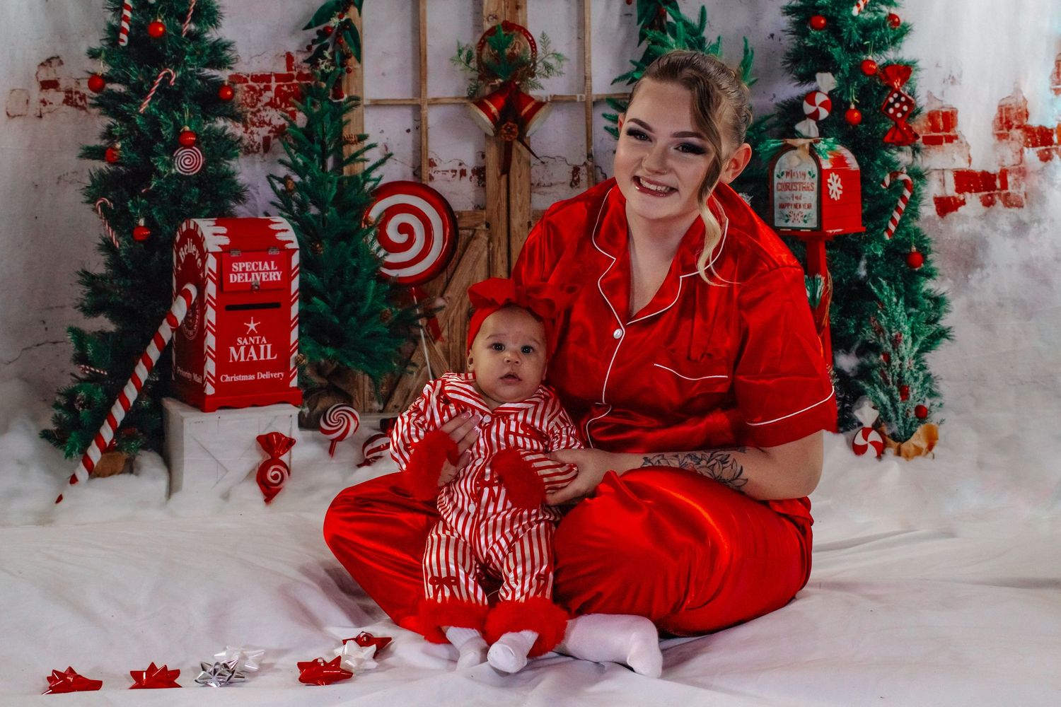 Mother and newborn baby wear matching red Christmas pajamas in holiday photo session.