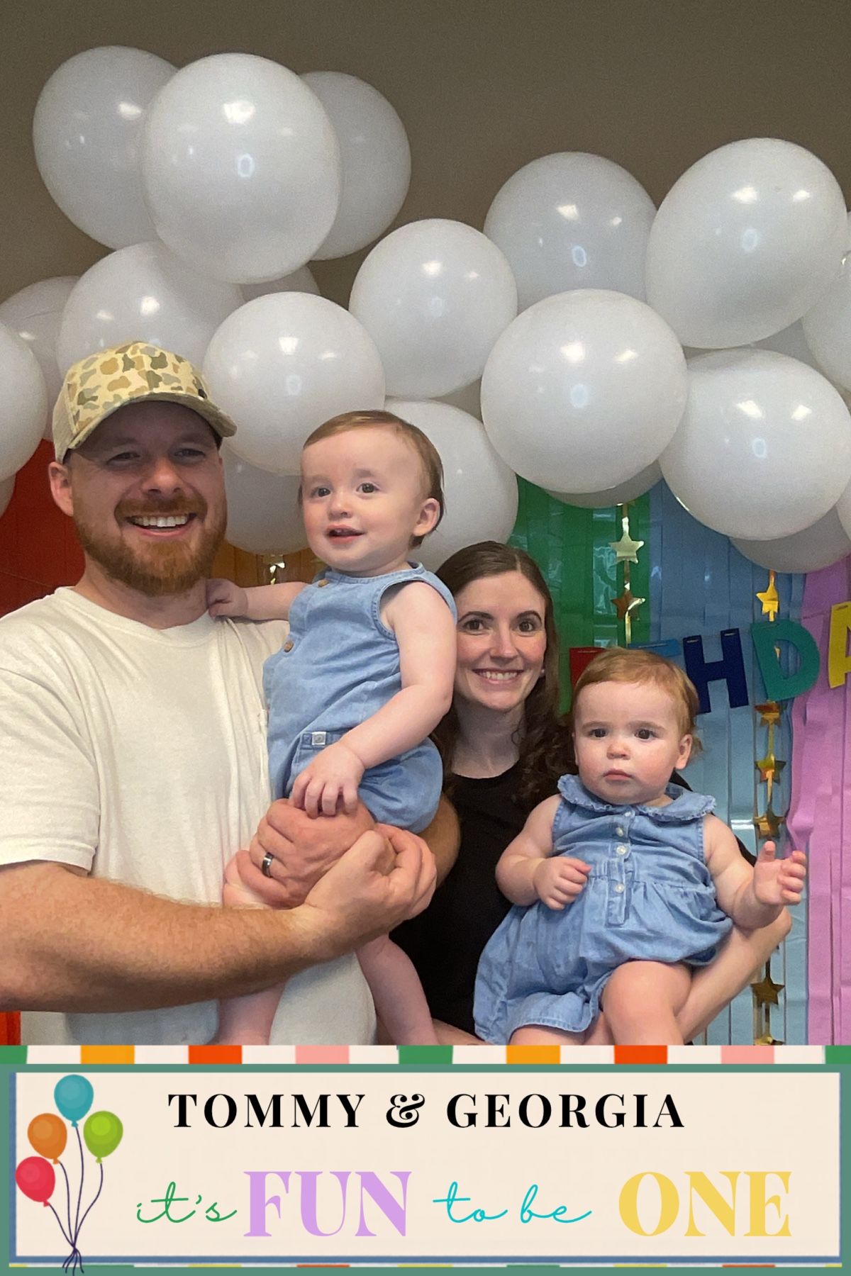 Family of four posing with white balloons at twins Tommy and Georgia's first birthday party celebration.