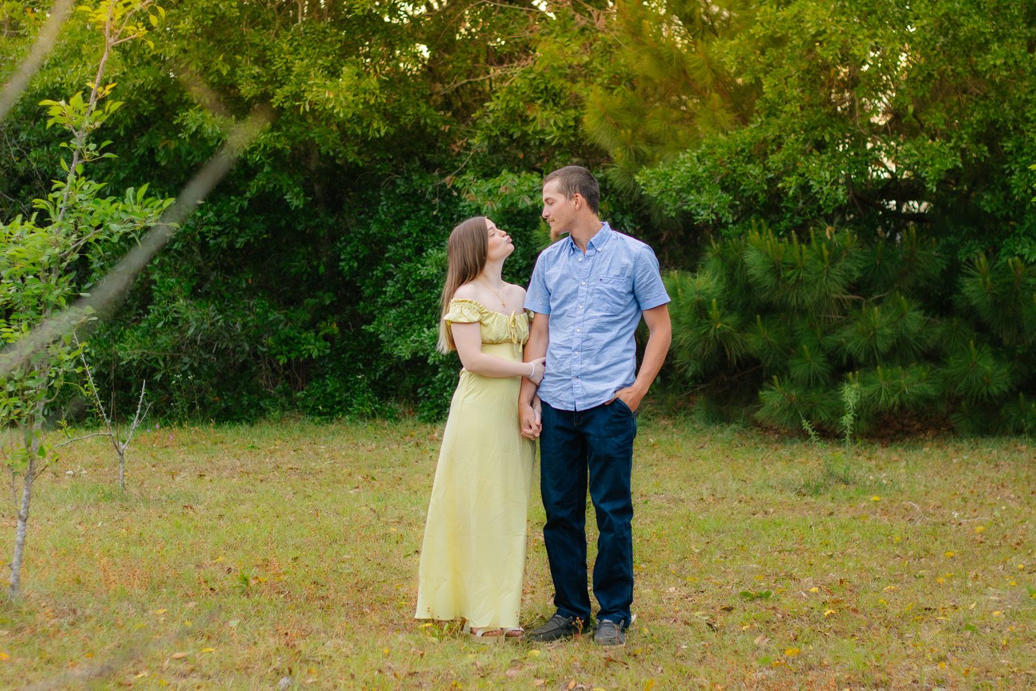 Young couple in casual attire gazing at each other in a scenic outdoor setting.