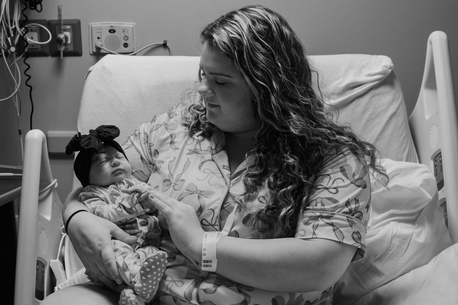 Black and white photo of new mother in hospital bed cradling her newborn baby.