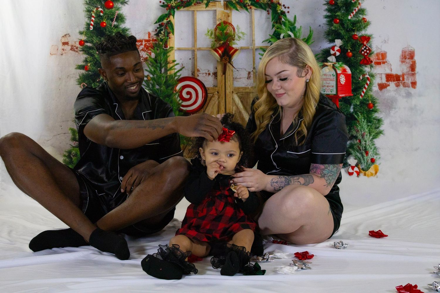 Family of three with toddler daughter pose together in matching black outfits for Christmas photos.