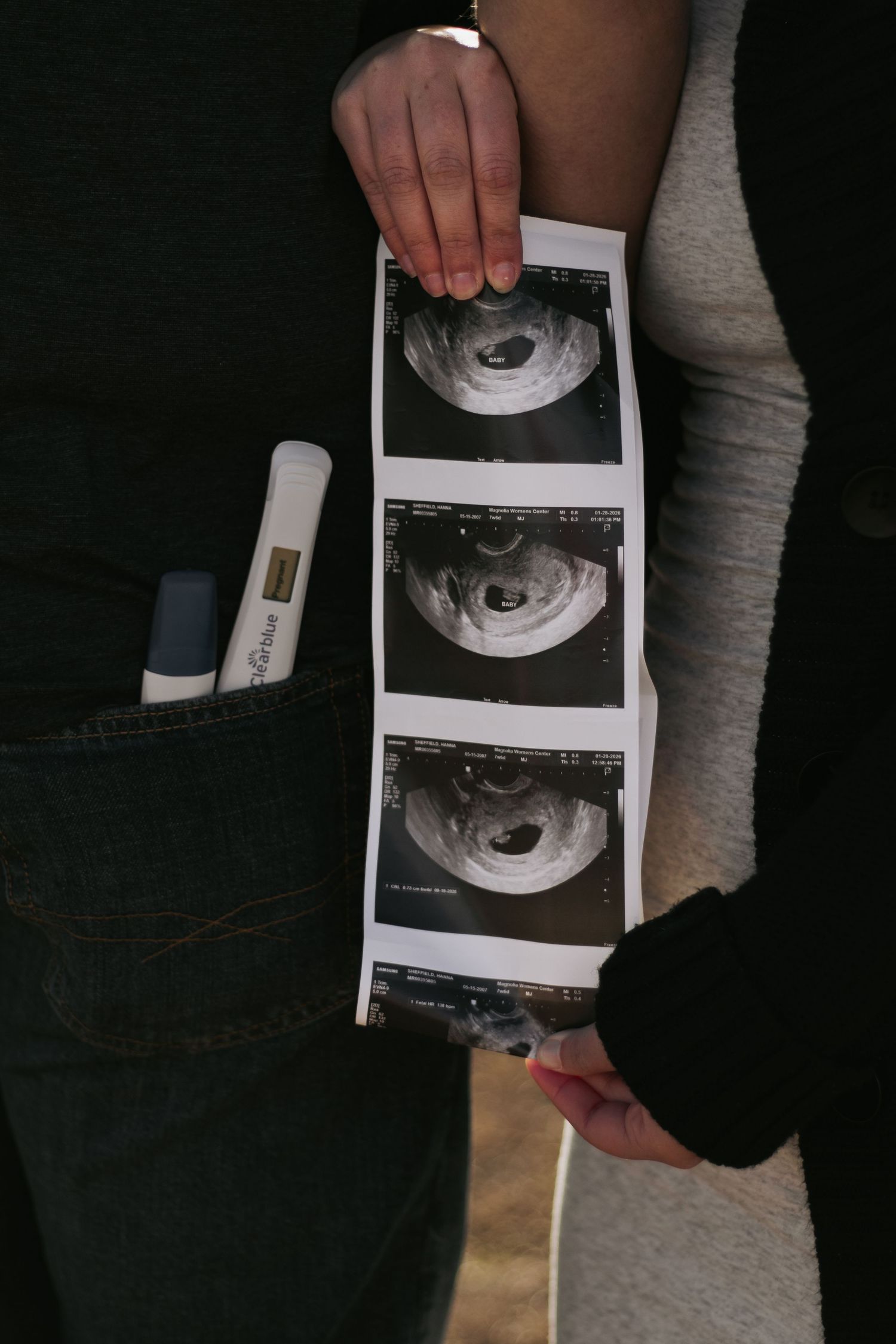 Couple holding ultrasound photos and pregnancy test during announcement.