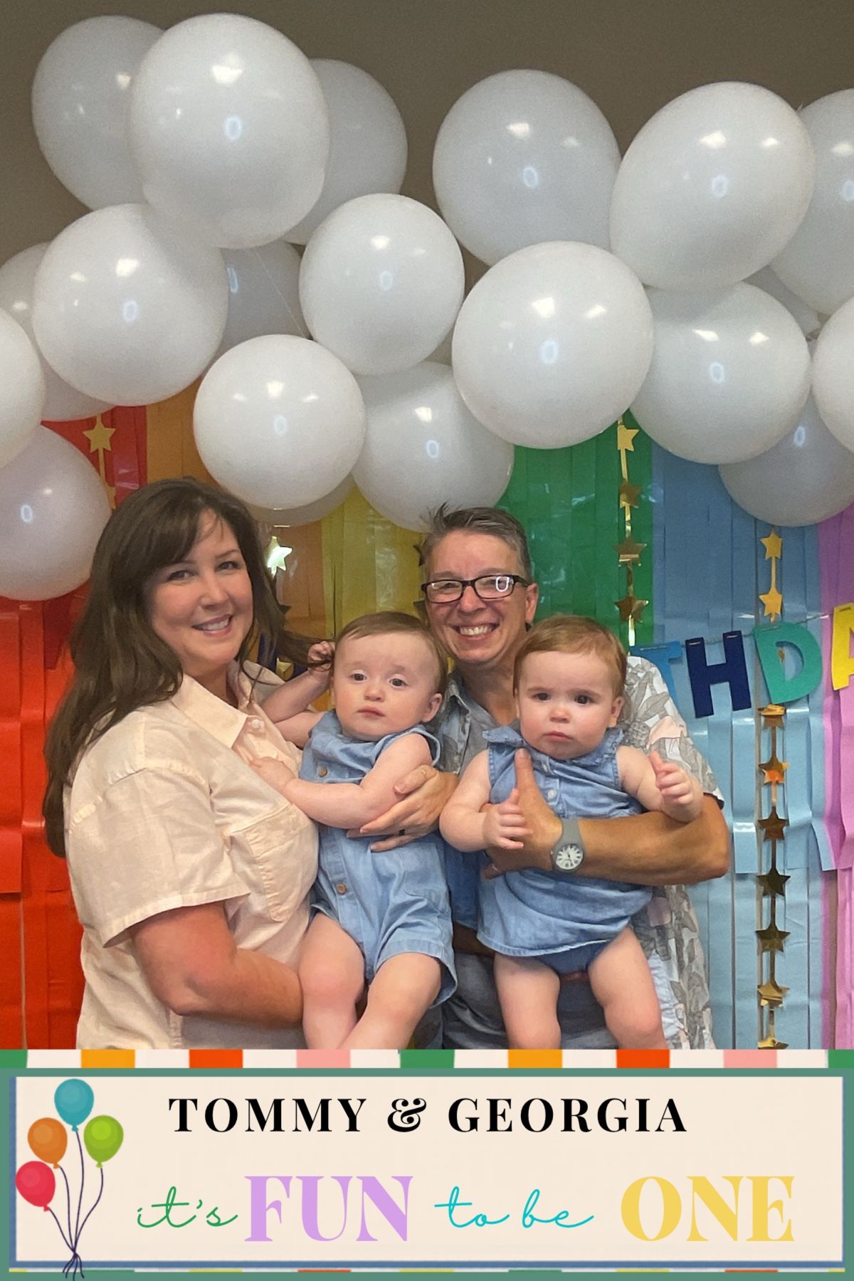 Two women holding twin babies Tommy and Georgia at their first birthday party with balloons.