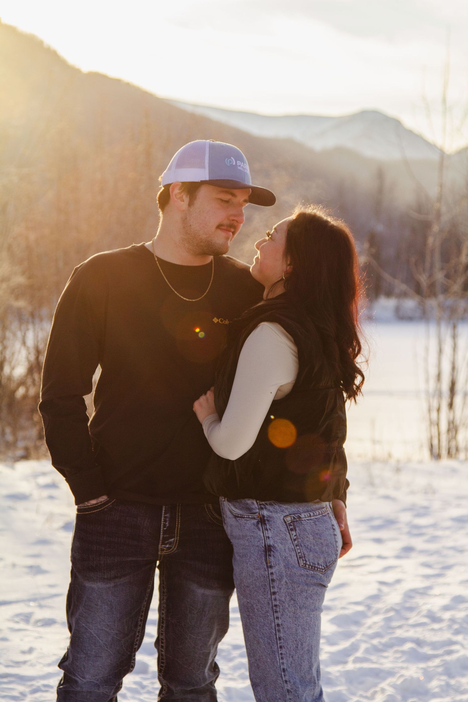 A couple shares romantic moments in a snowy winter landscape at sunset, captured in a series of intimate poses.