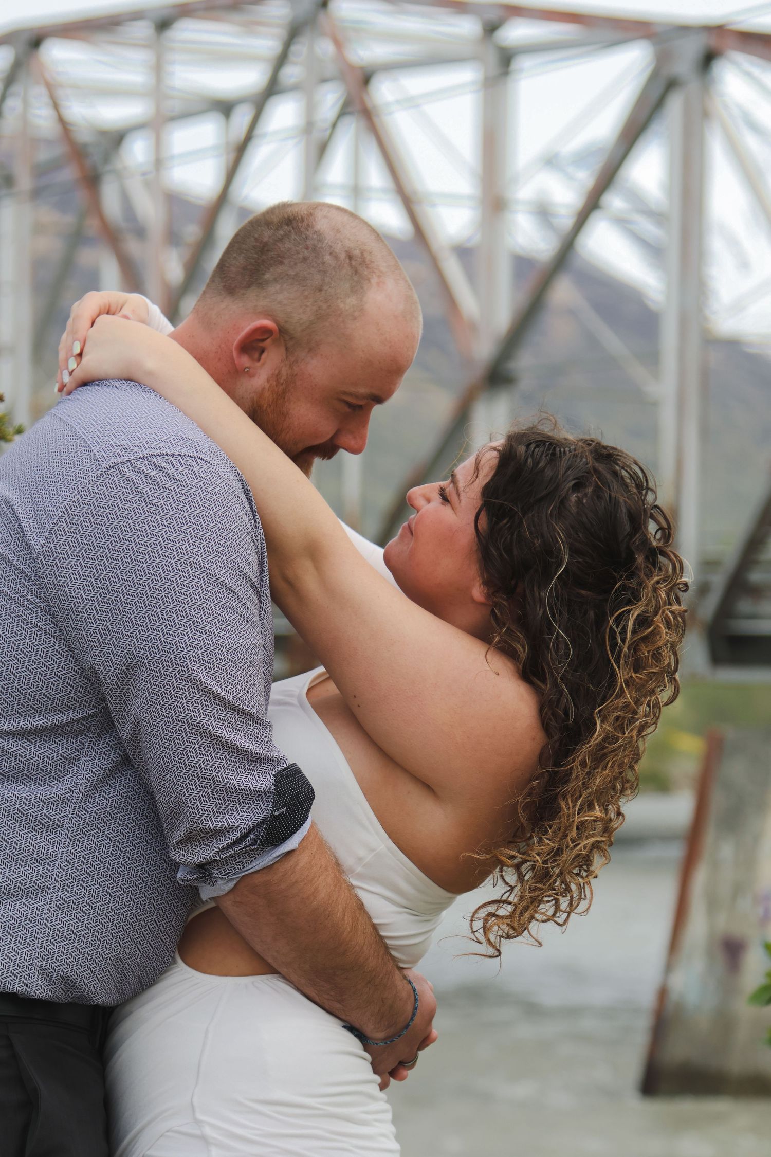 A romantic couple embraces and shares intimate moments in a series of tender poses under a glass-roofed structure.