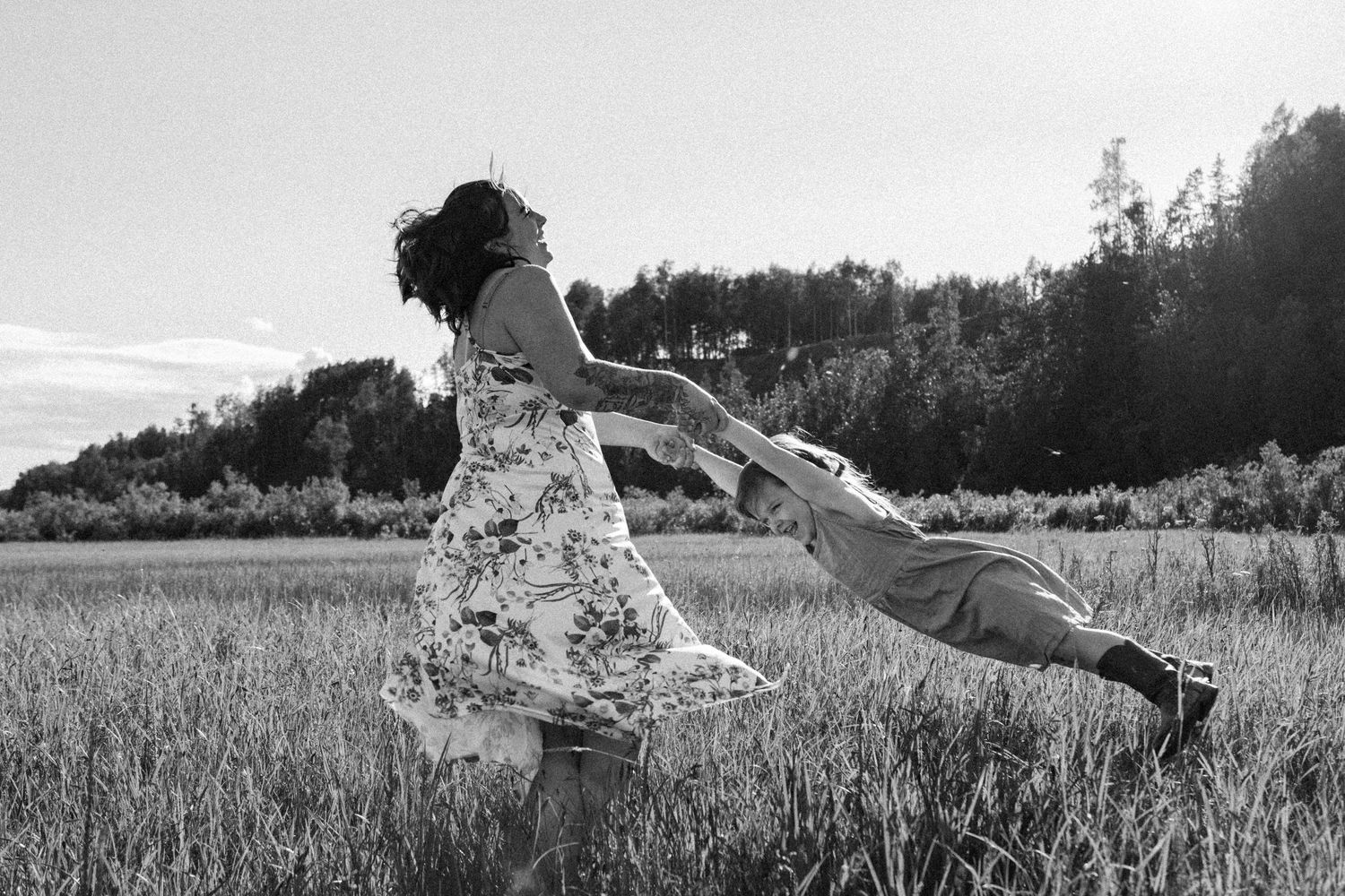 A sequence of black and white photographs showing someone gracefully floating and jumping through a grassy meadow.