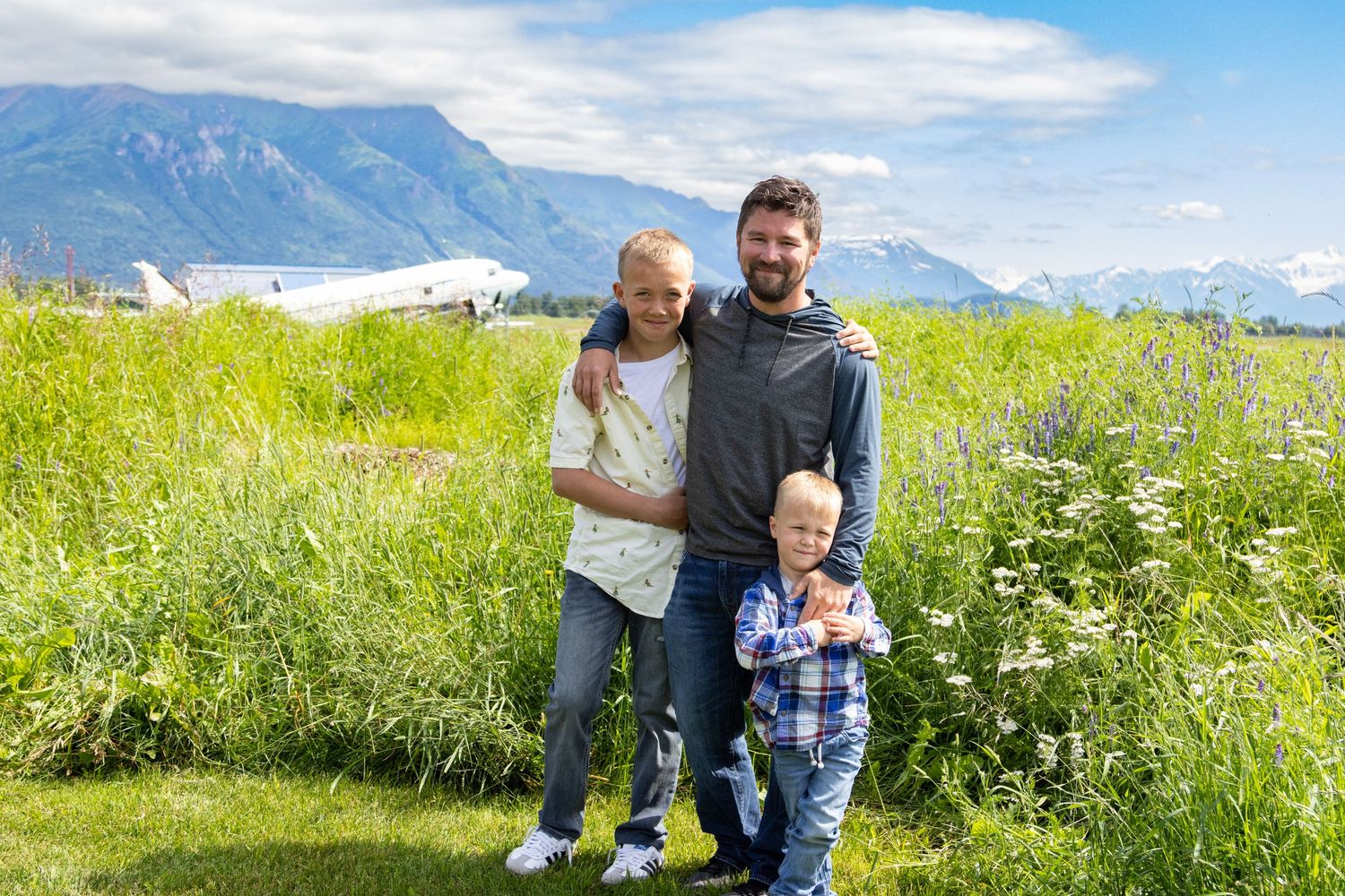 People exploring a scenic mountain meadow filled with wildflowers on a sunny summer day in the Alps.
