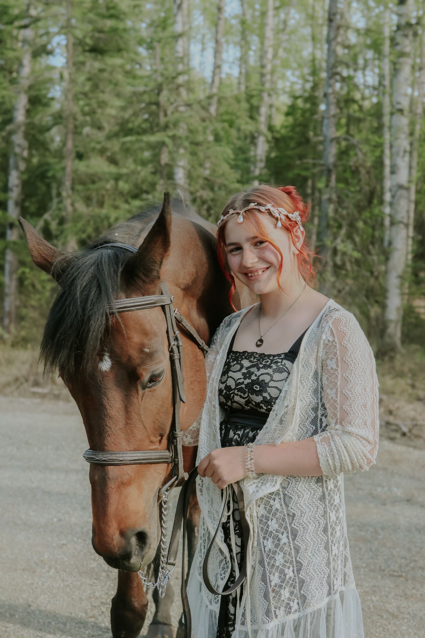 A brown horse stands beside a person wearing a black dress and white lace shawl in a wooded setting.