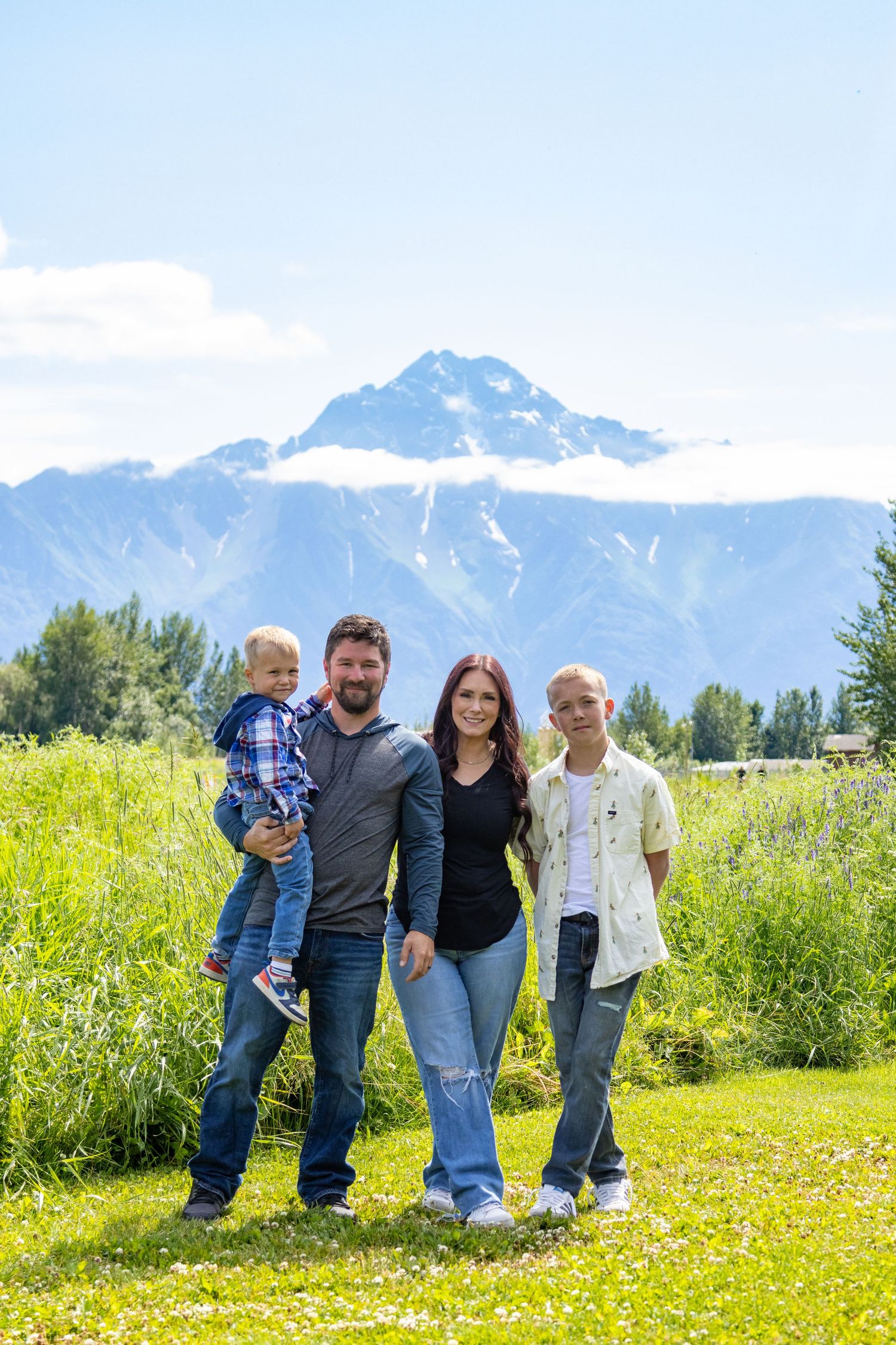 Group enjoying a summer day in a meadow with majestic snow-capped mountain peaks rising in the background.