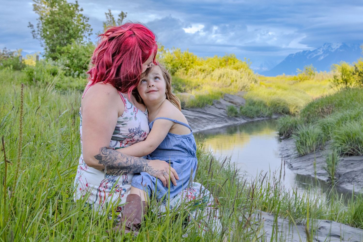 Two people embrace in a romantic moment outdoors with golden wildflowers and natural scenery in the background.
