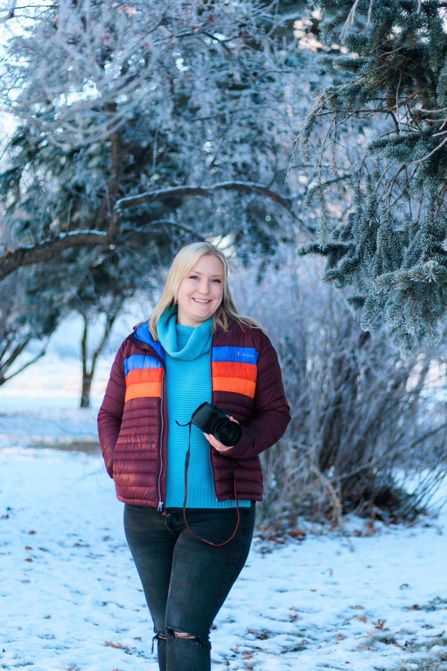 Winter outdoor portrait in snowy forest with colorful striped puffer jacket and bright blue scarf.