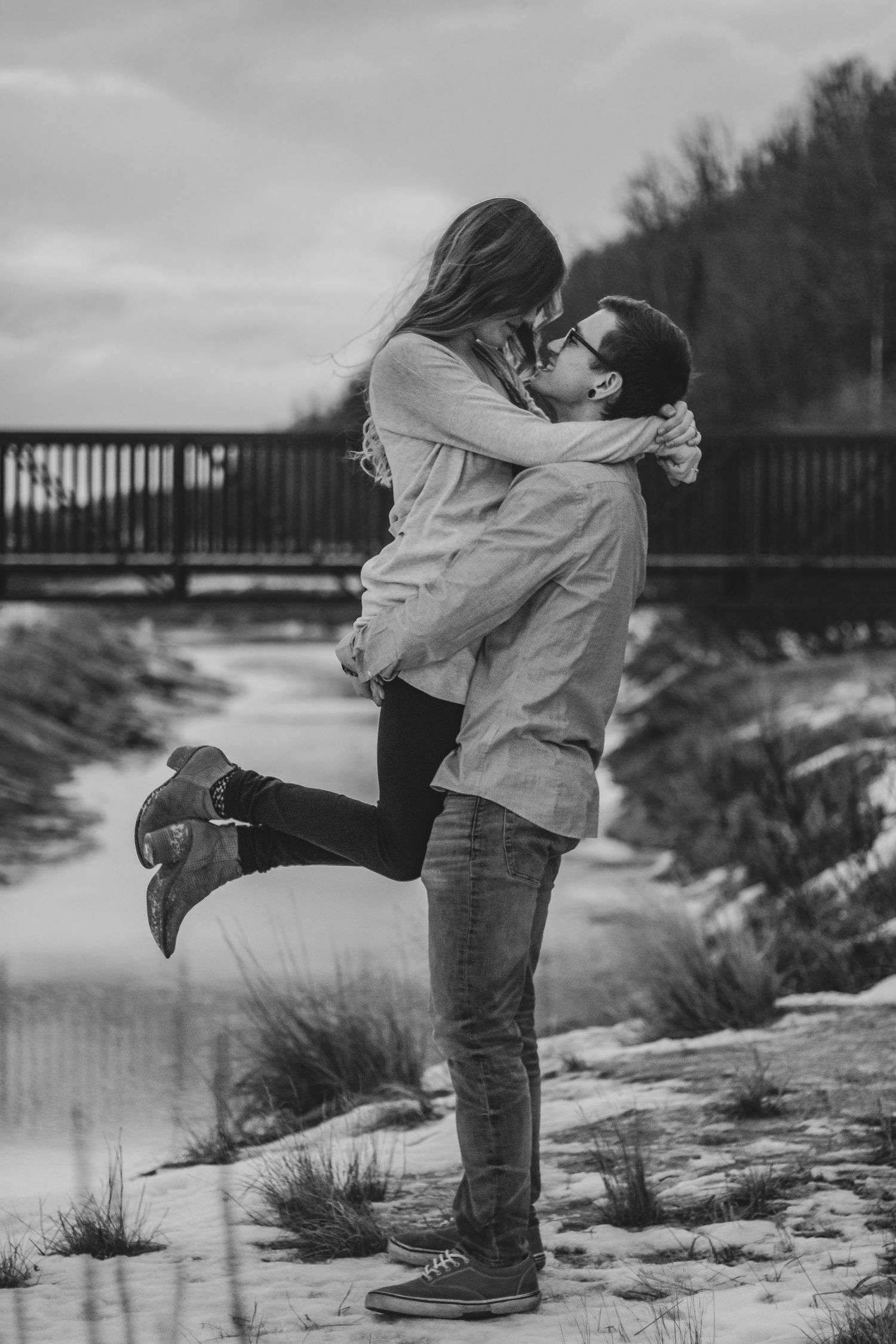 A romantic black and white photo sequence showing a couple embracing and lifting each other by a riverside.