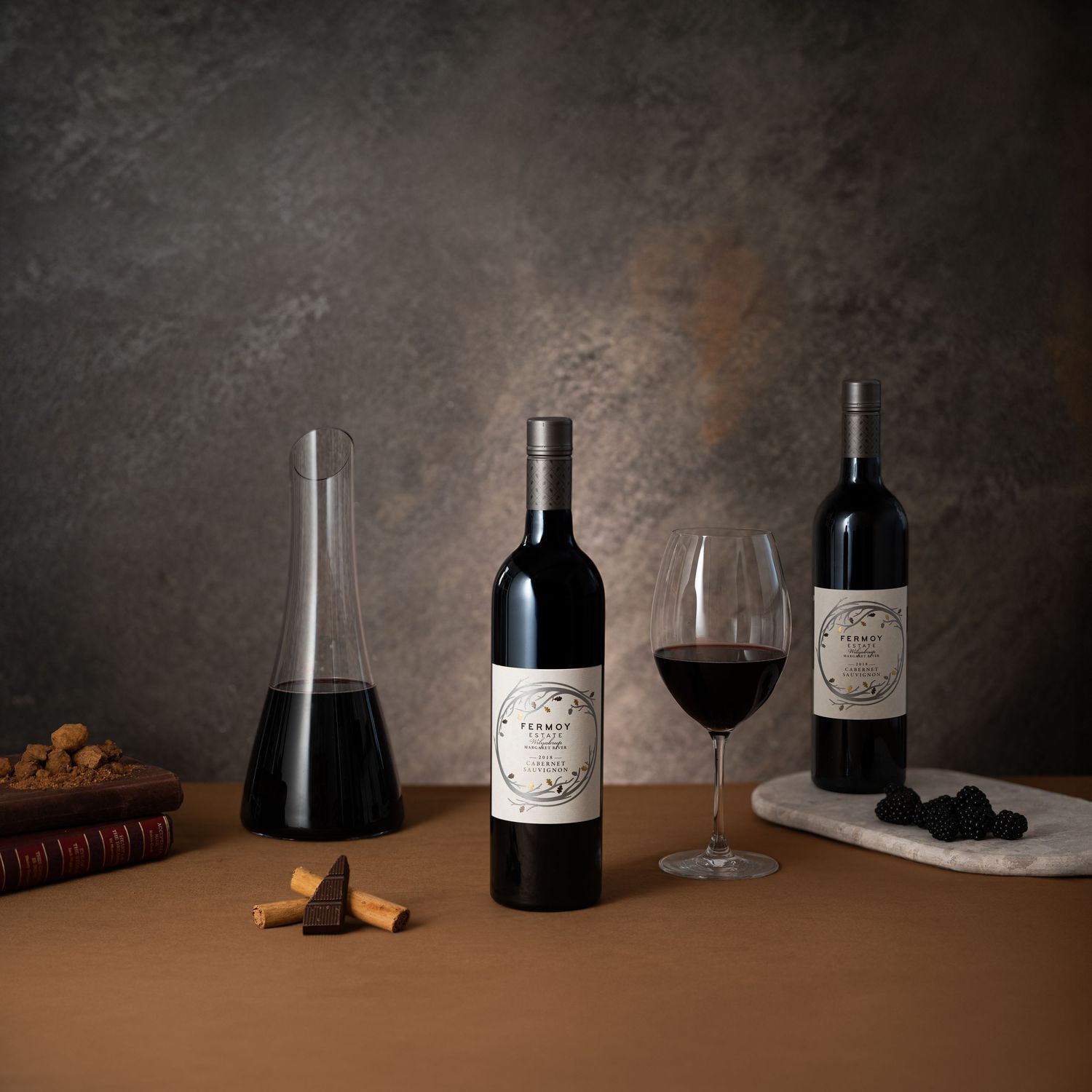 Two bottles of Tempo red wine displayed with a glass decanter and a full wine glass on a brown surface.