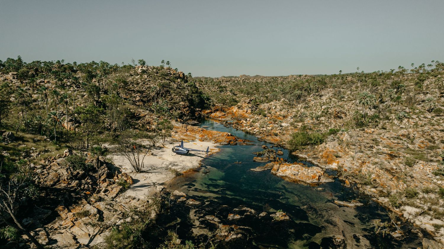 Aerial view of a remote rocky river winding through rugged Australian wilderness.