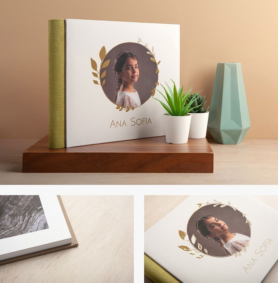 White hardcover photo album with gold foil wreath and girl portrait displayed on wooden stand with succulent.