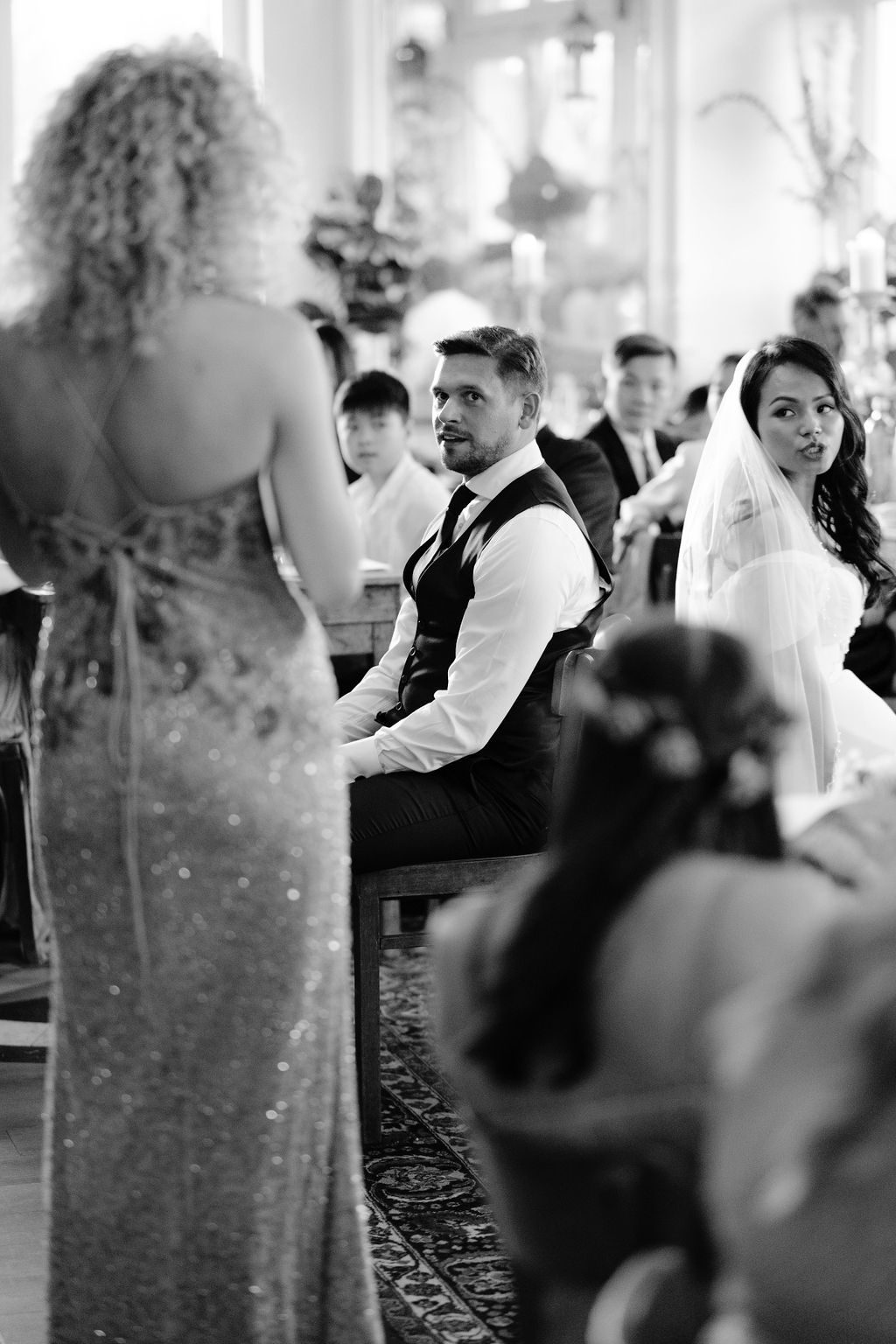 Black and white wedding photos displayed in a filmstrip style showing candid reception moments in an elegant venue.