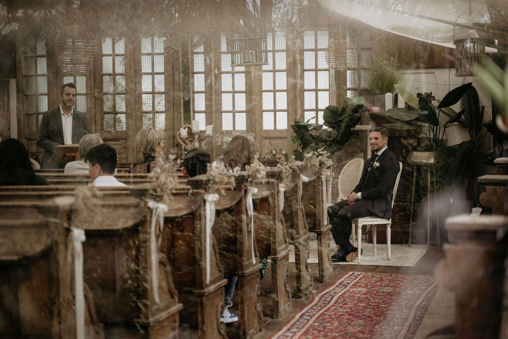 Vintage sepia-toned image of a factory interior showing workers at wooden tables under large windows.
