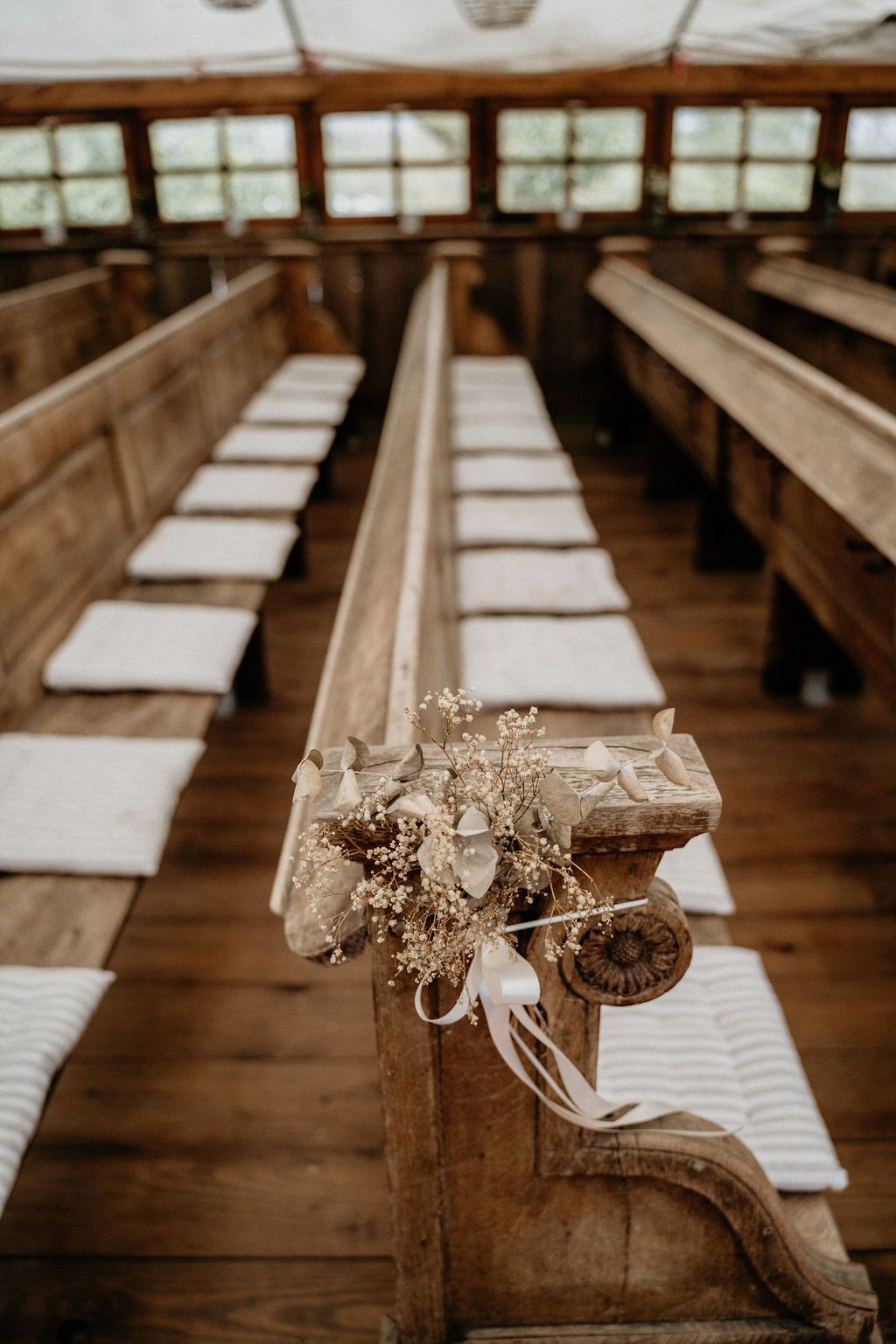 Sepia-toned church pews cast long shadows in a rustic wooden chapel with natural light streaming through windows.