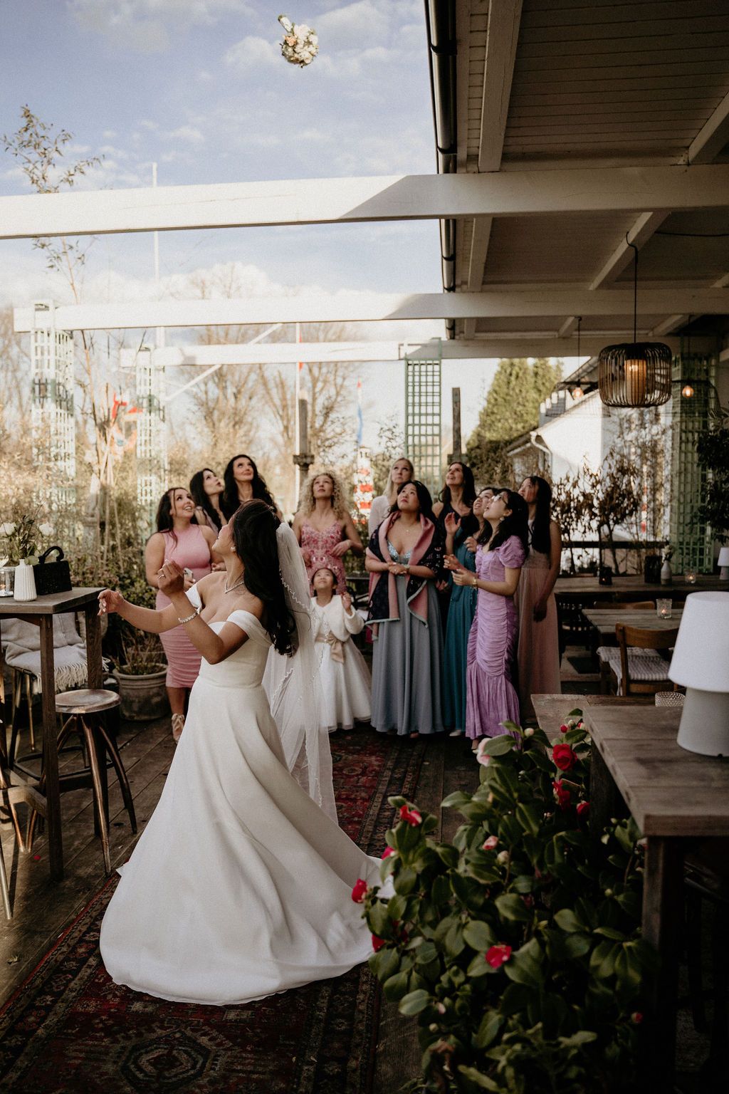 A wedding celebration with elegant decor in a covered outdoor venue with a mix of gray and purple bridal party dresses.