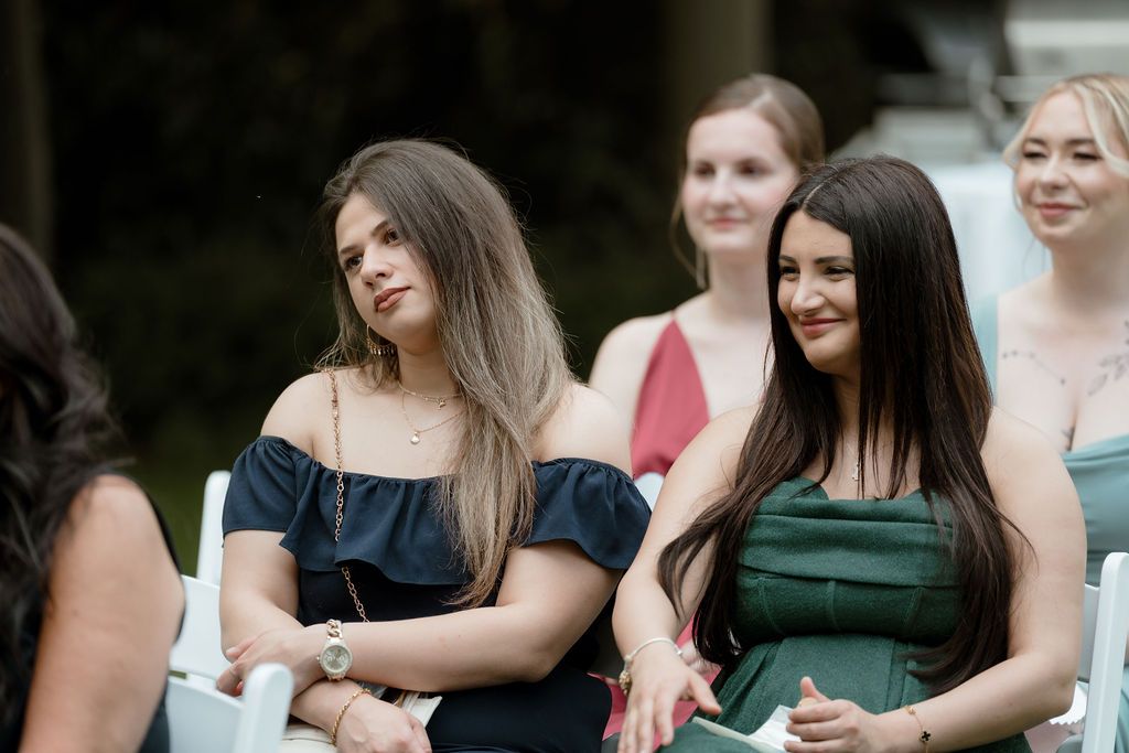 A group of young women in formal dresses gather together and smile during a social event.