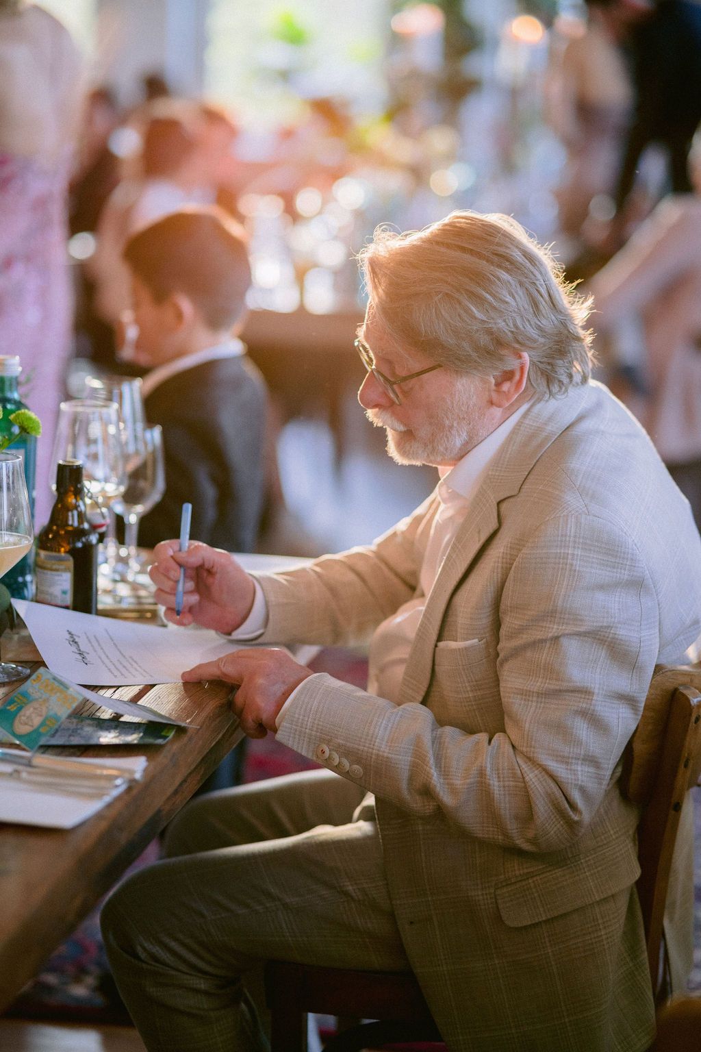 A sequence of candid shots capturing a person in a white jacket sitting at a dining table during an event.