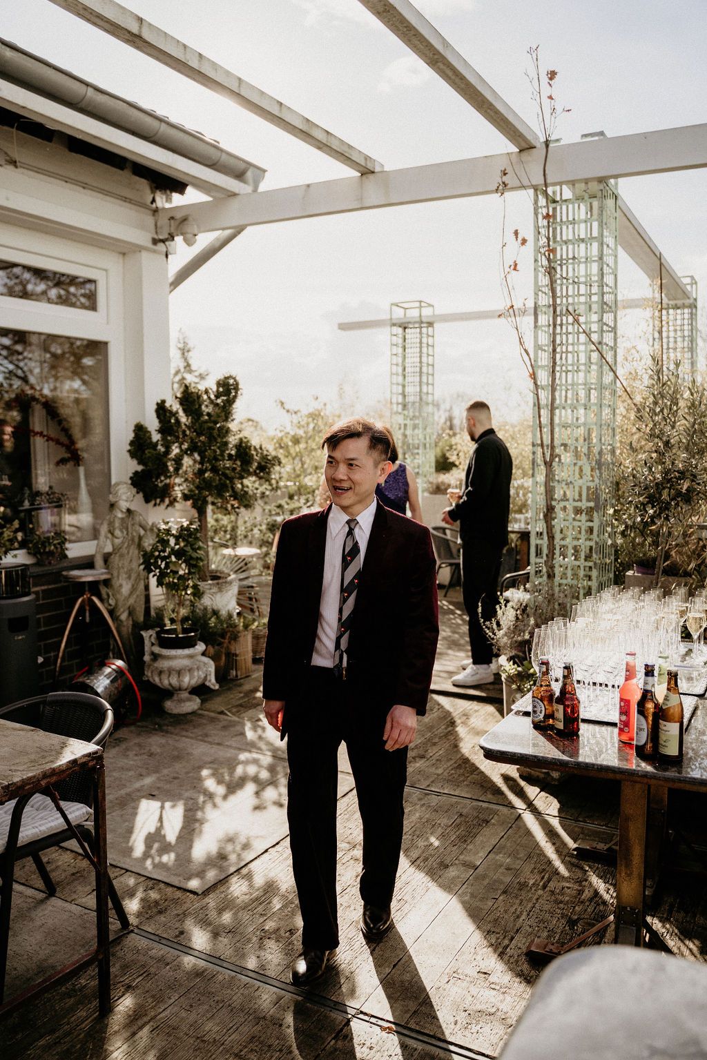 Elegant rooftop venue setup with outdoor seating and decor under white beams during golden hour.