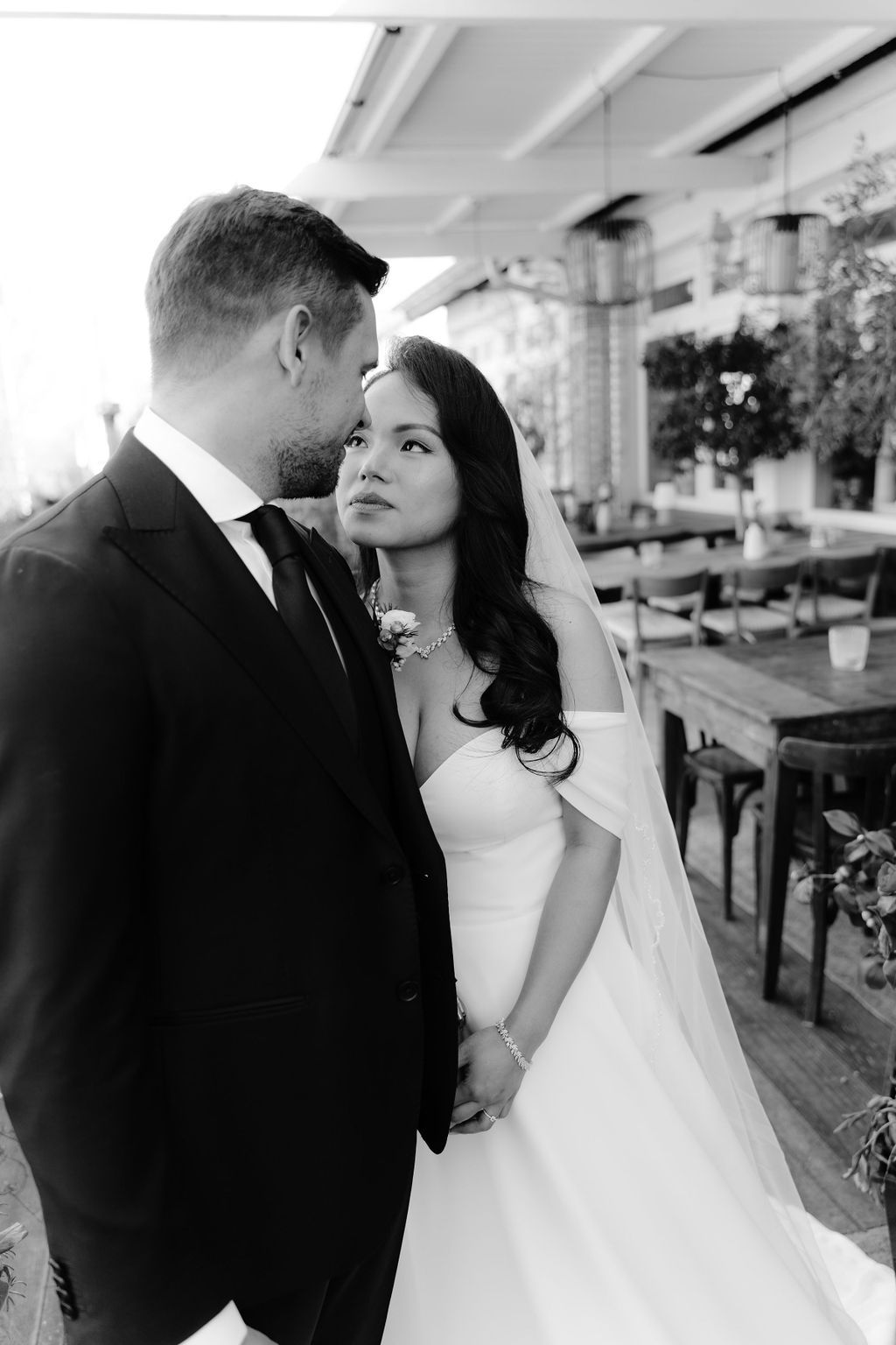 Black and white romantic wedding portraits showcase tender moments between newlyweds against an outdoor backdrop.