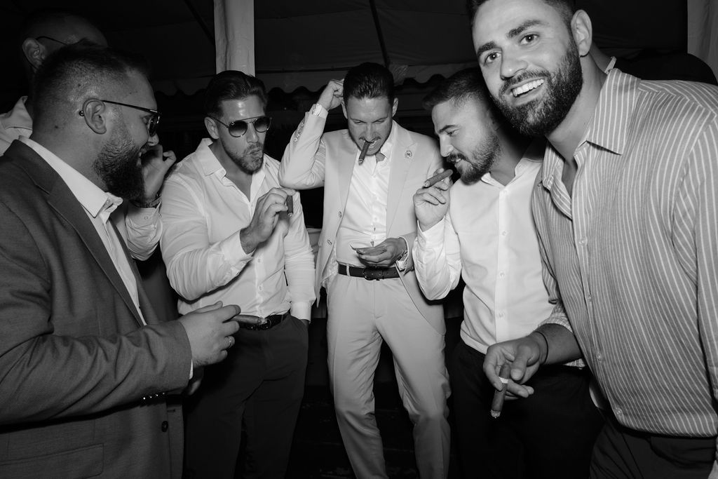 A group of friends in formal attire sharing drinks and laughter at a black and white party celebration.