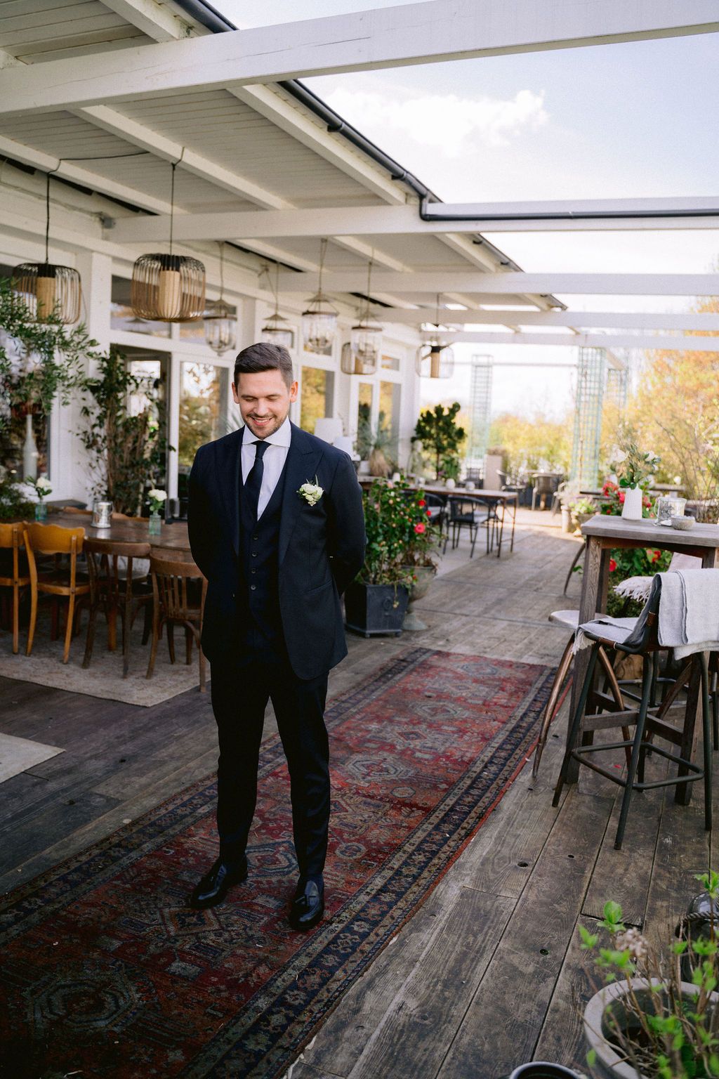 A wedding scene on an open-air terrace decorated with vintage rugs, potted plants and rustic wooden furniture.