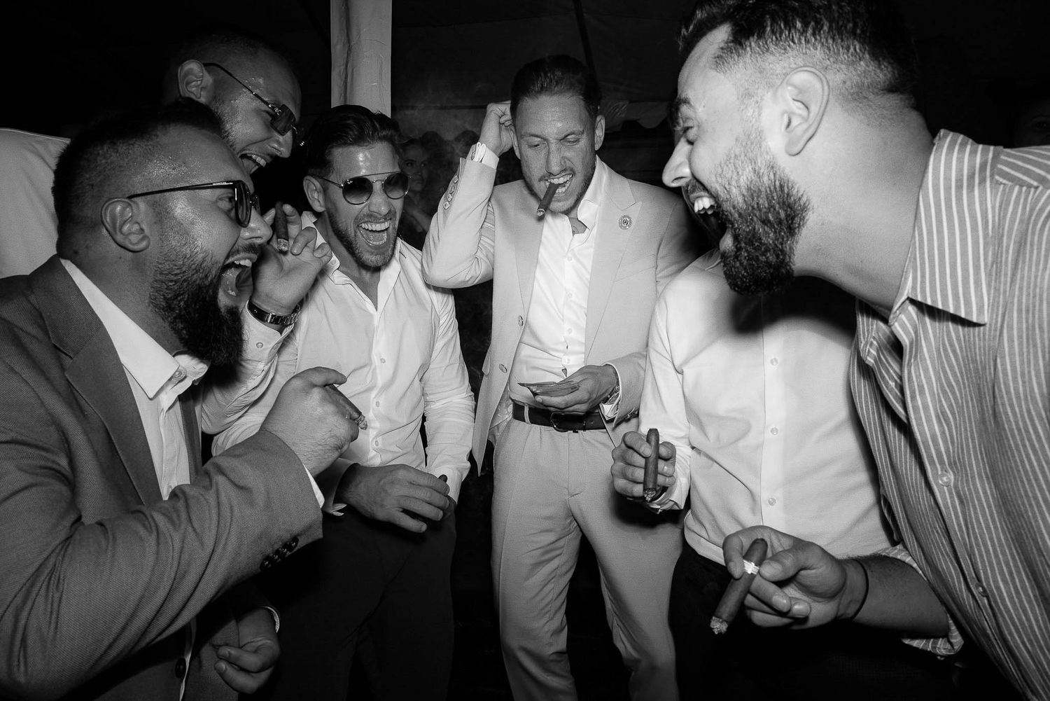 A group of people laughing and having a good time at a party, captured in black and white photography.