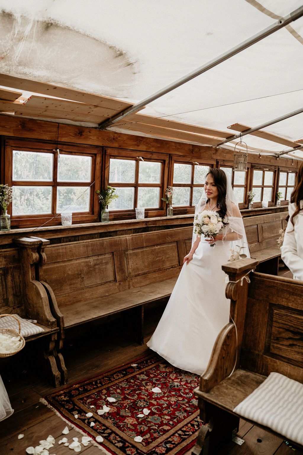 A vintage wooden church interior with rustic pews and an ornate red carpet runner creates a romantic atmosphere for a wedding.