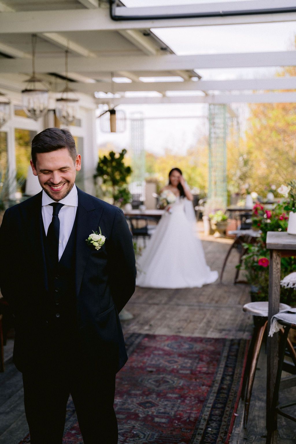 Wedding ceremony moments captured at an outdoor venue with autumn trees and decorative rugs on a patio.