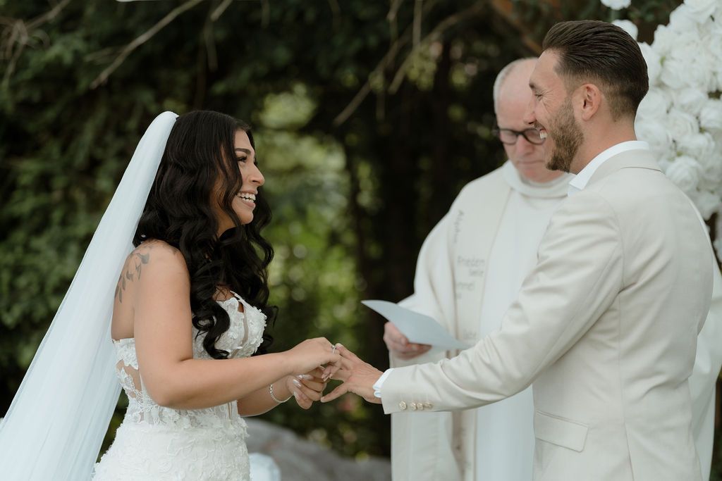 A couple in matching white wedding attire dance together on an outdoor patio during their first dance celebration.
