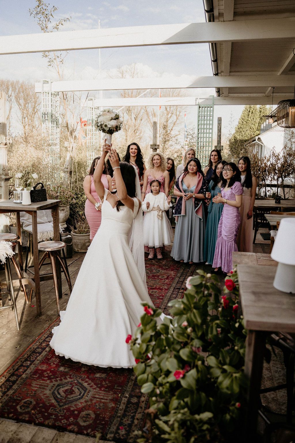 Wedding party gathered in a rustic venue with soft lighting and oriental rugs creates a warm, intimate atmosphere.